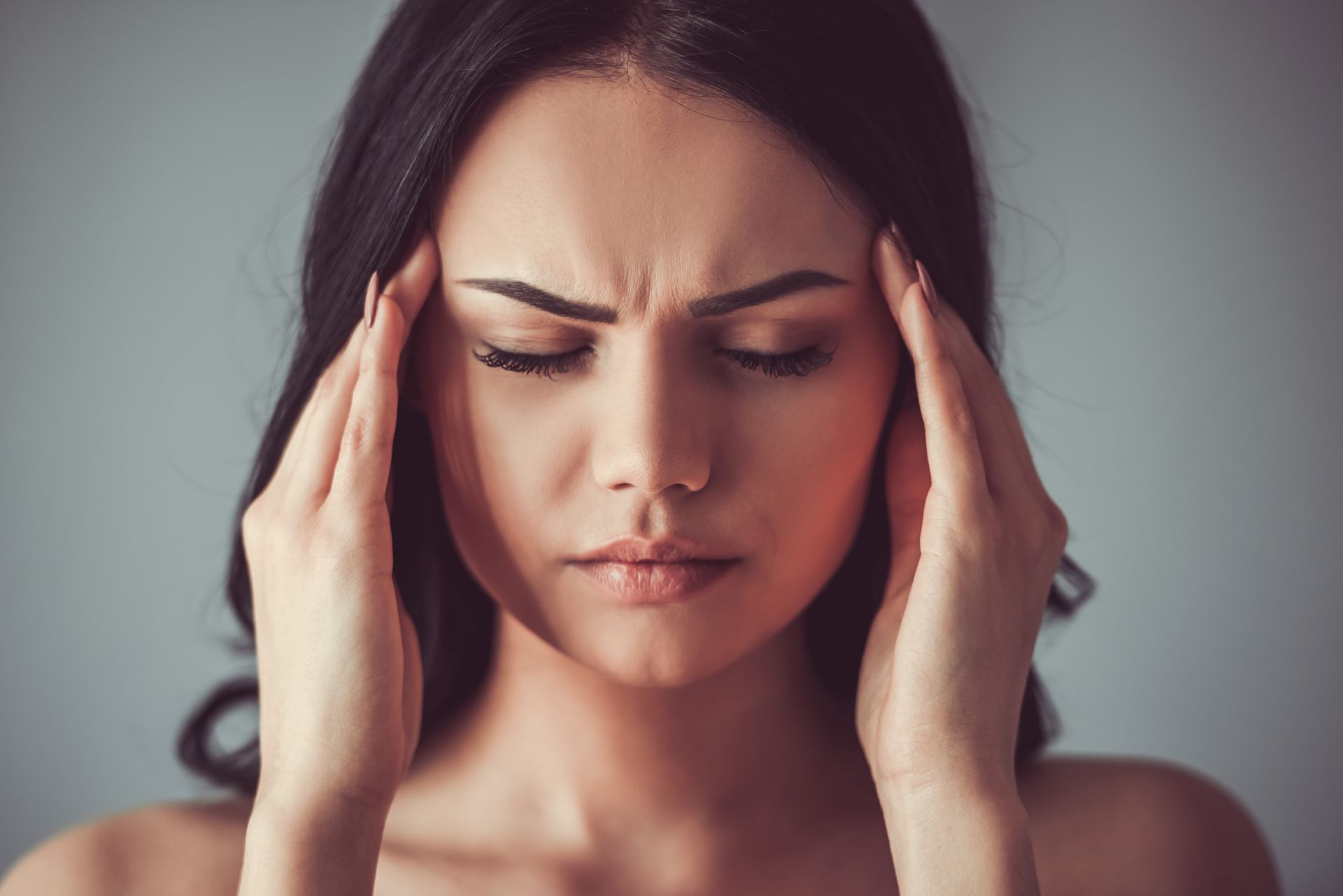 A woman is holding her head in pain.