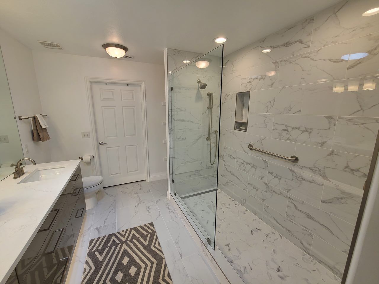 A bathroom with a walk in shower , sink and toilet.