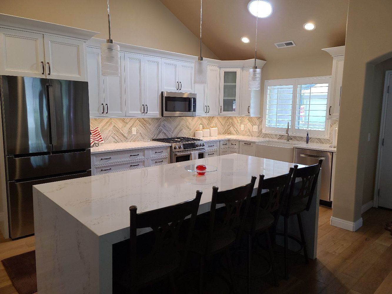 A kitchen with white cabinets , stainless steel appliances and a large island.