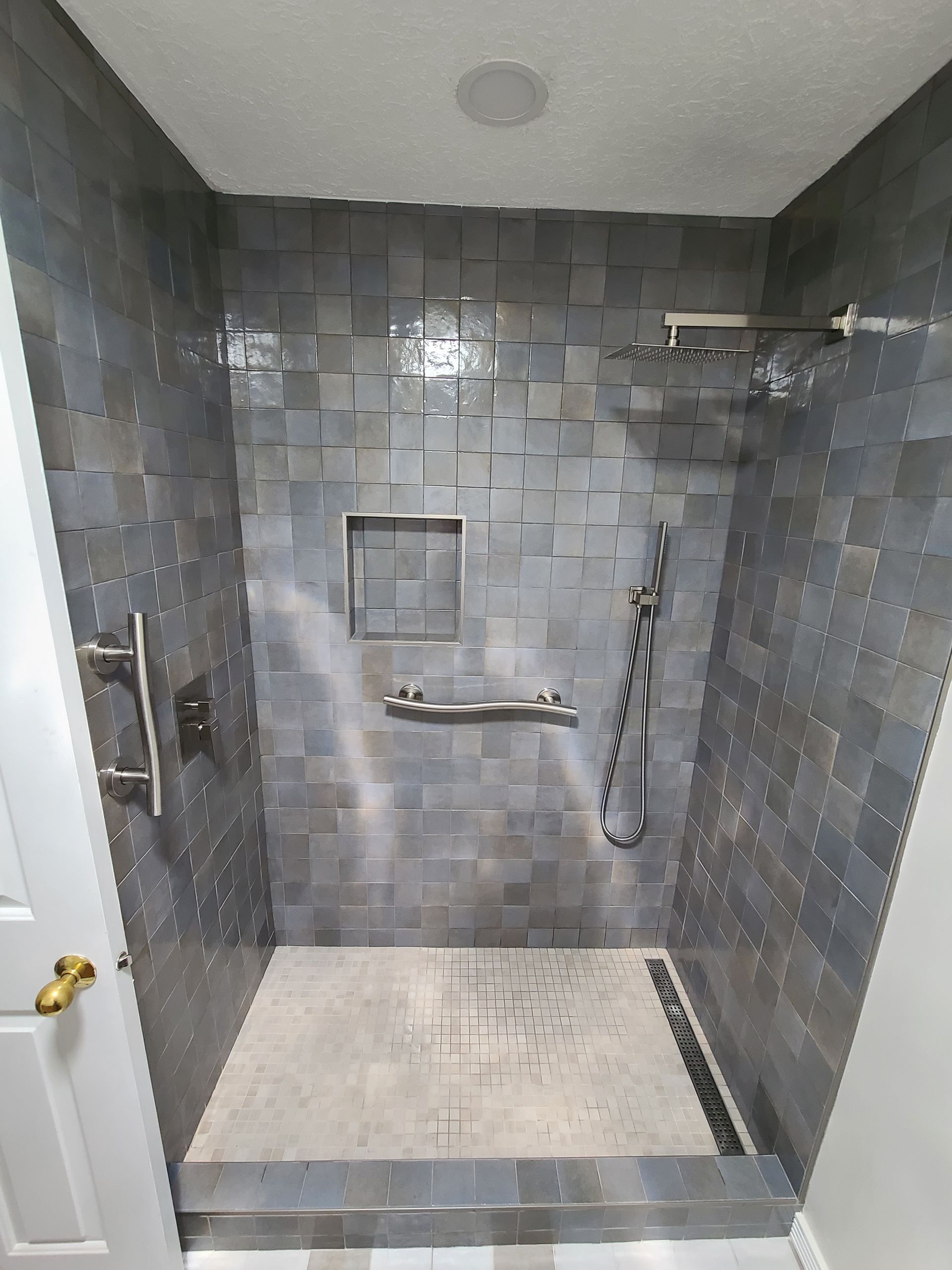 A bathroom with a walk in shower and a shower head.