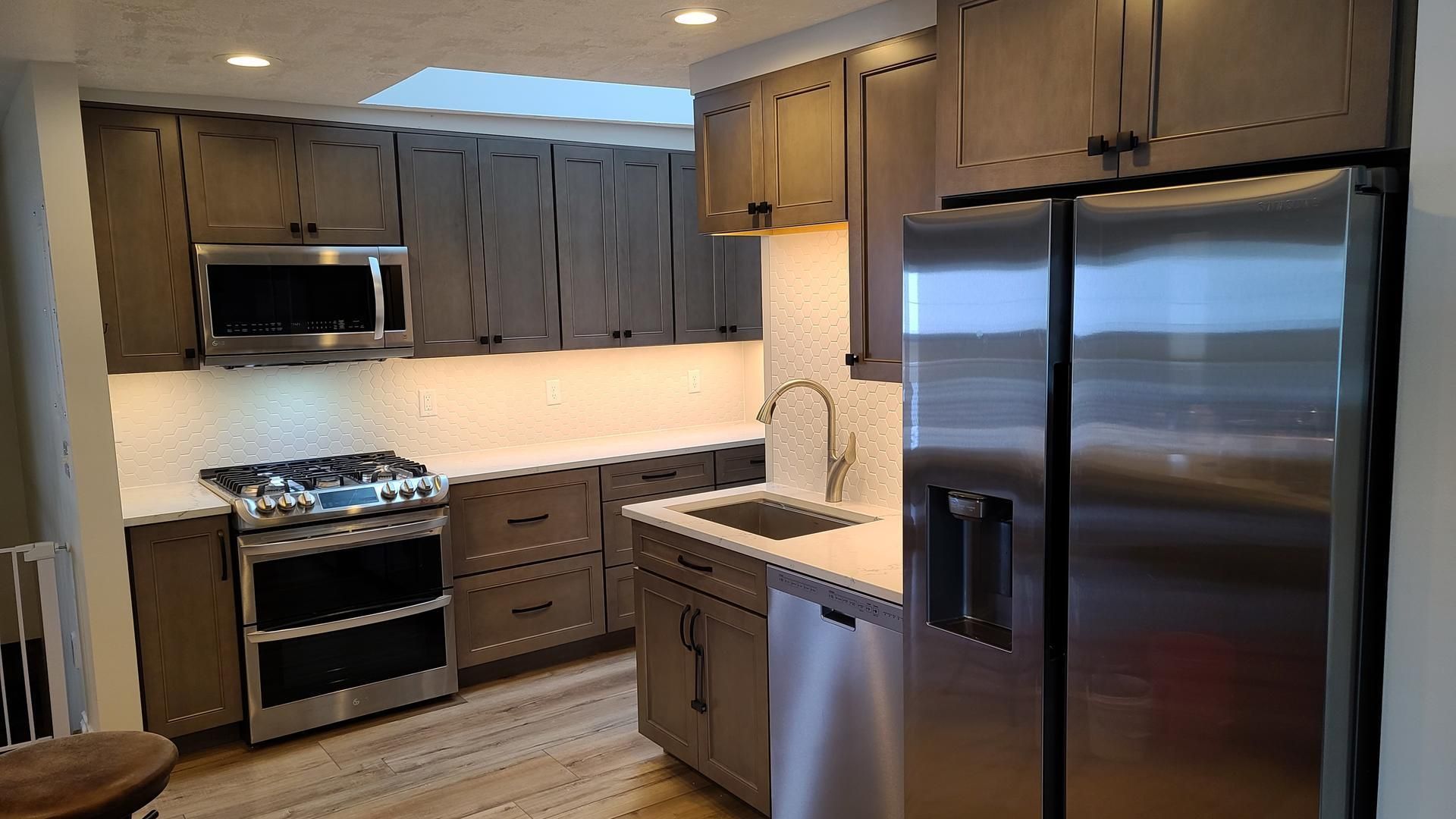 A kitchen with stainless steel appliances and gray cabinets.
