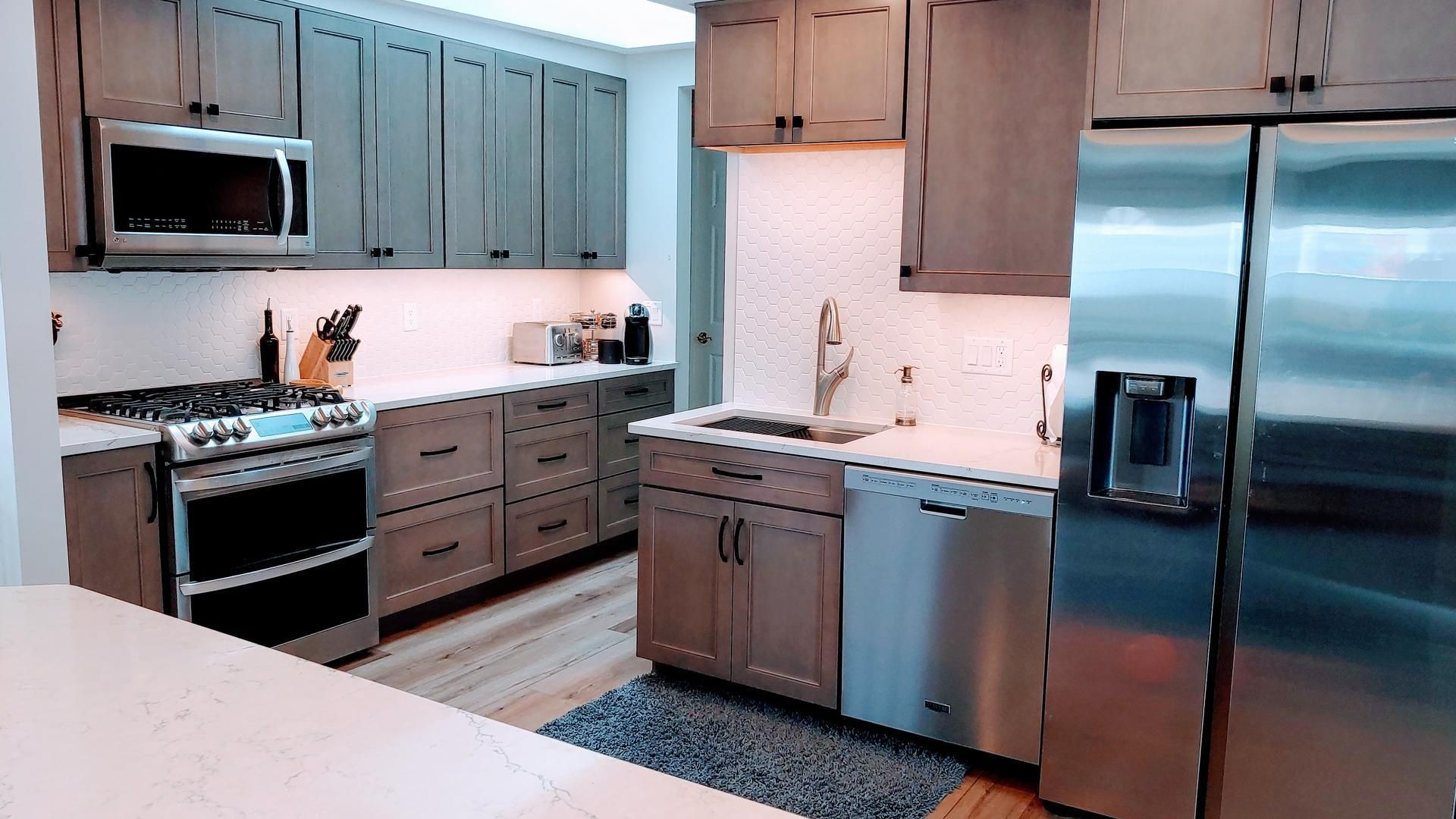 A kitchen with stainless steel appliances and gray cabinets.