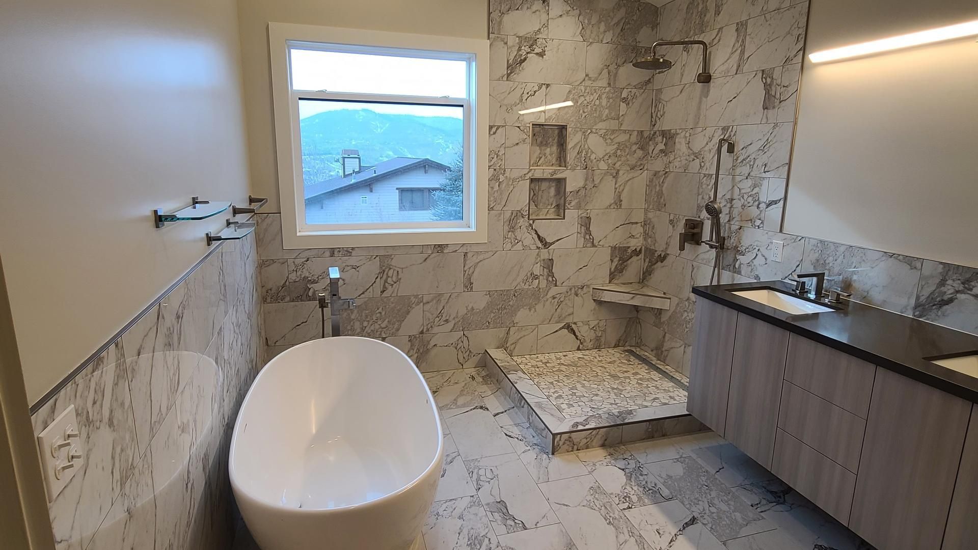 A bathroom with a tub , sink , shower and window.