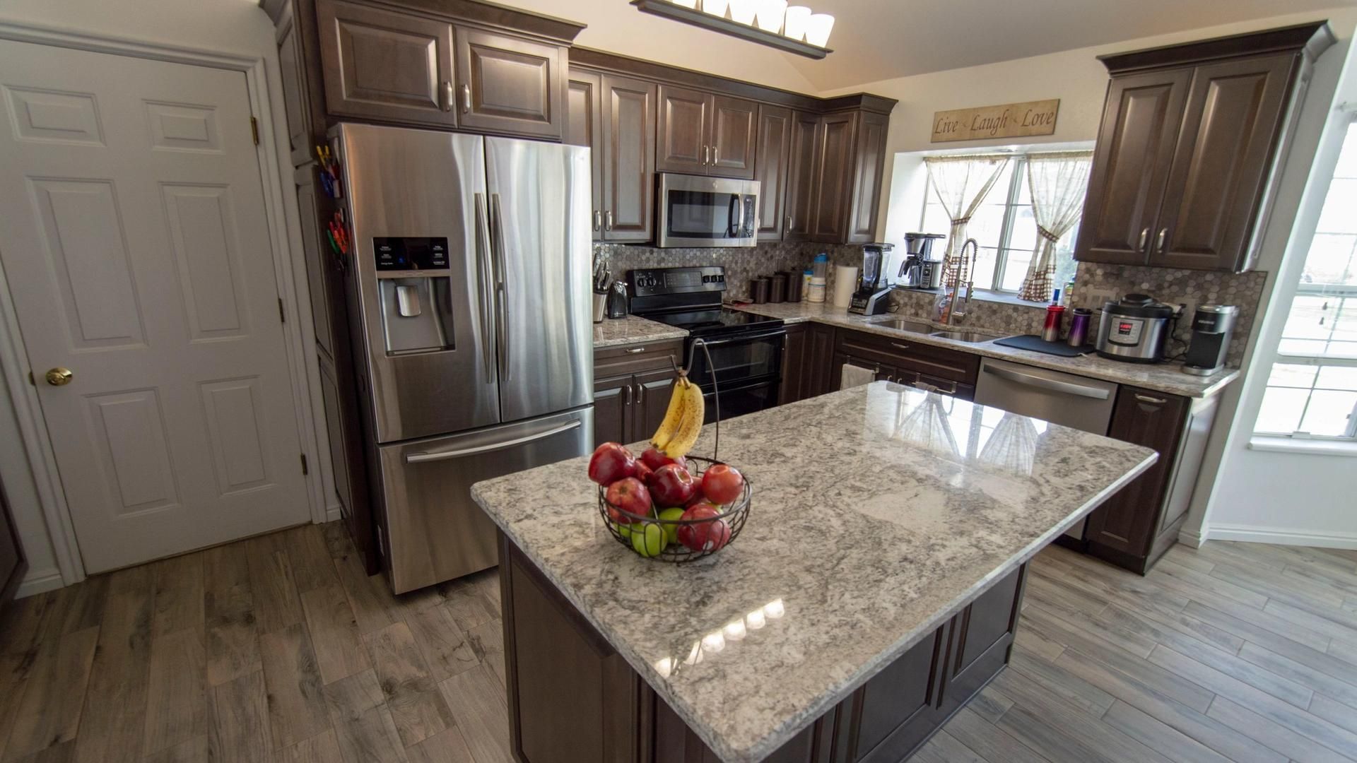 A kitchen with stainless steel appliances , granite counter tops , and a large island.