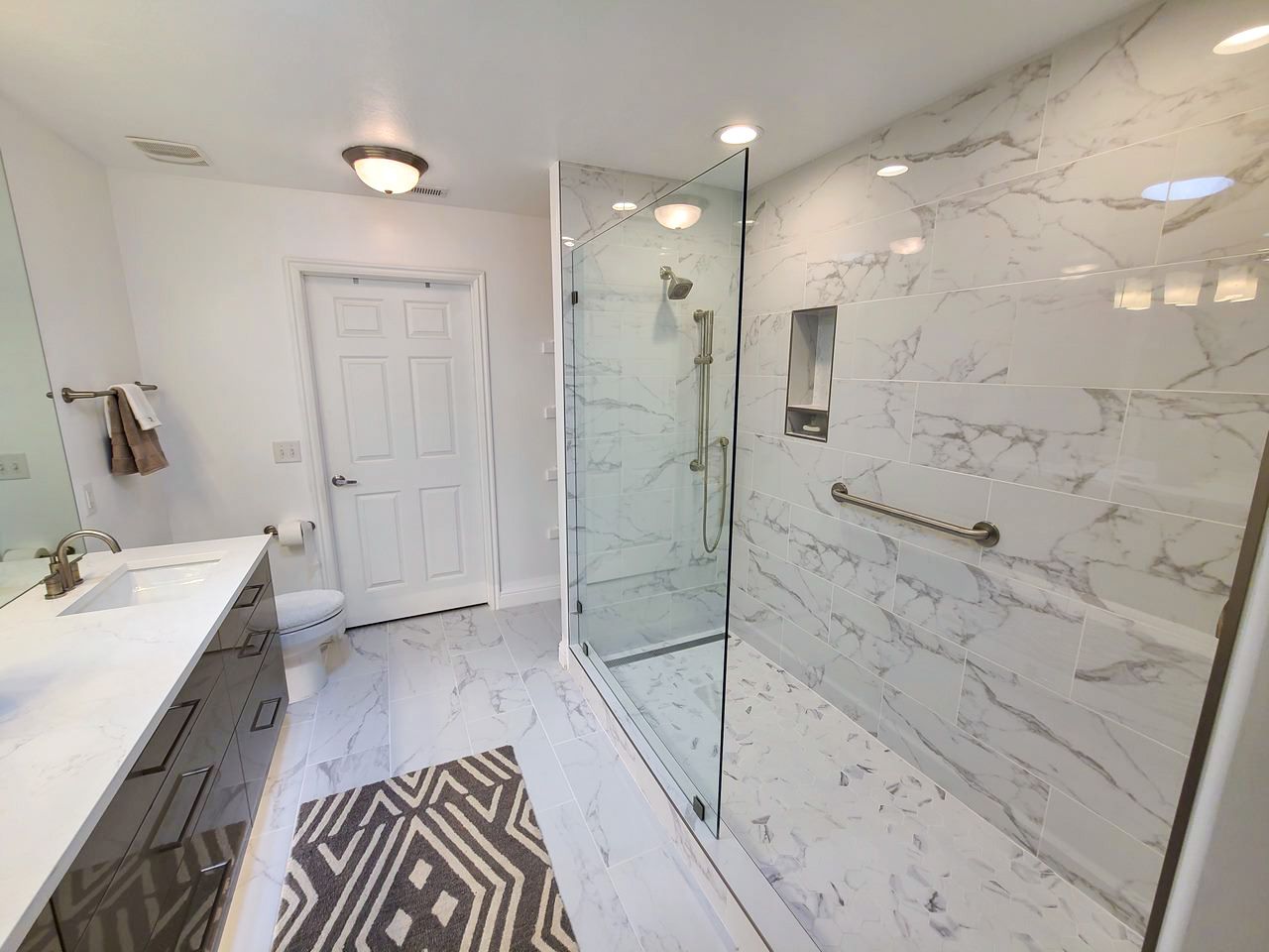 A bathroom with a walk in shower , sink and toilet.