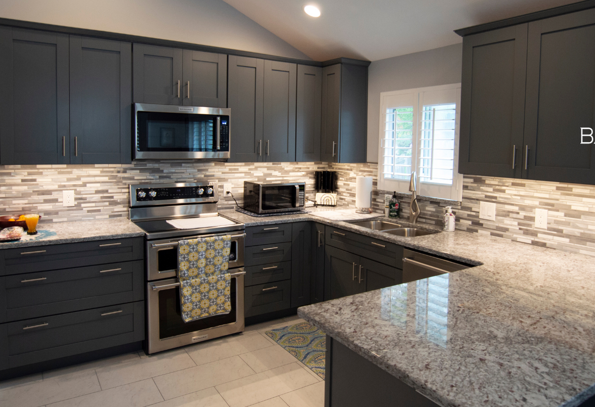 A kitchen with gray cabinets and granite counter tops