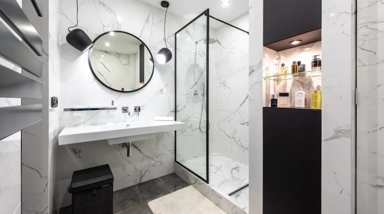 A bathroom with a sink , mirror and walk in shower.