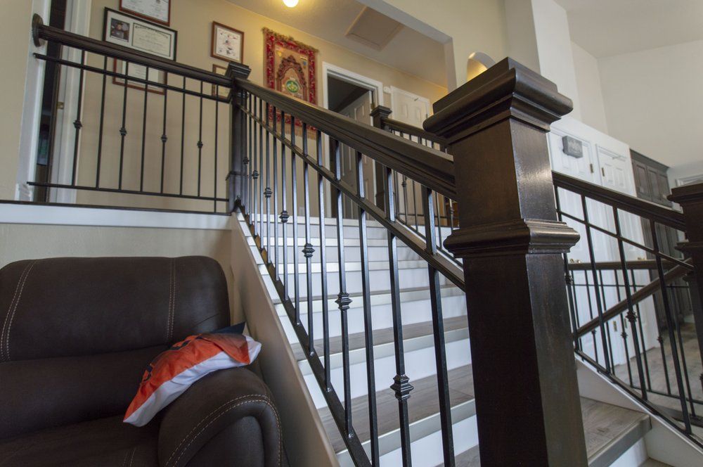 A staircase with a black railing and a brown chair