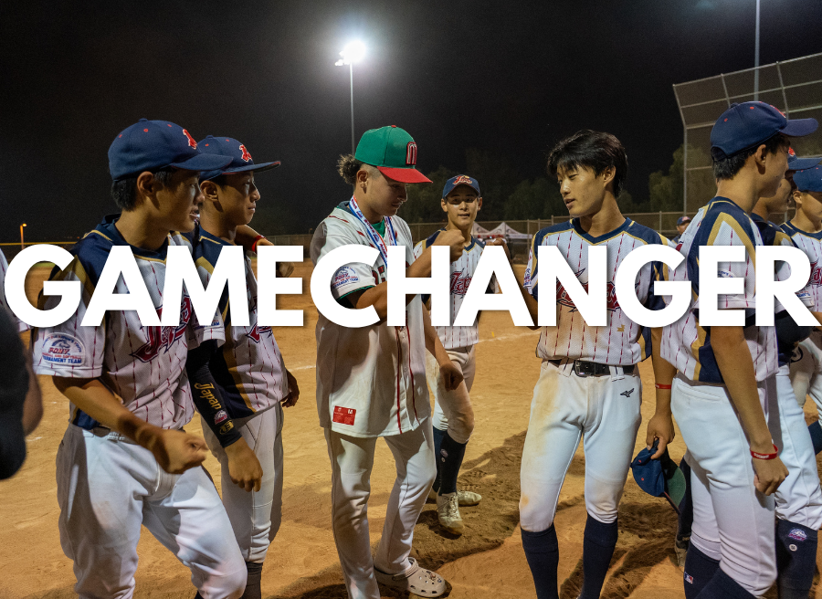 Youth baseball players huddle on a lit dirt field at night, with “GAMECHANGER” overlaid across the image.