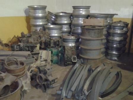 Pila de llantas de coche, piezas de vehículos y componentes metálicos dentro de un espacio de almacenamiento.