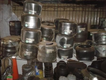 Bobinas de tubos negros apiladas en un espacio de almacenamiento poco iluminado.