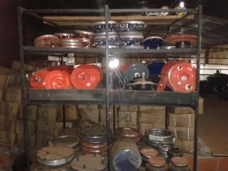 Estantes llenos de diversas piezas industriales de color rojo, azul y plateado dentro de un almacén.