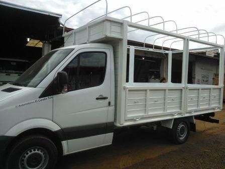 Furgoneta de carga blanca con estructura metálica, estacionada al aire libre.