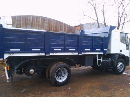 Camión volquete azul y blanco estacionado afuera; la caja del camión está elevada.
