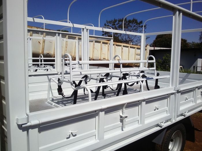Camión de transporte de ganado con plataforma de metal blanco, estilo al aire libre, estacionado al aire libre en un día soleado.