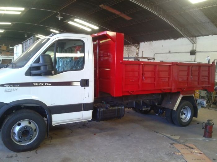 Camión volquete blanco y rojo en un taller.