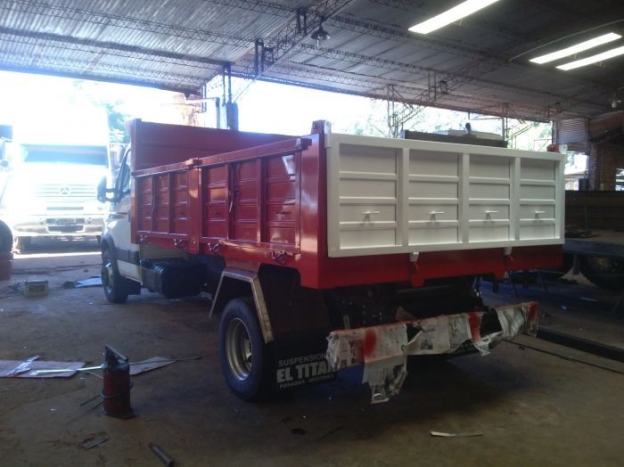 Camión volquete rojo y blanco en un garaje.