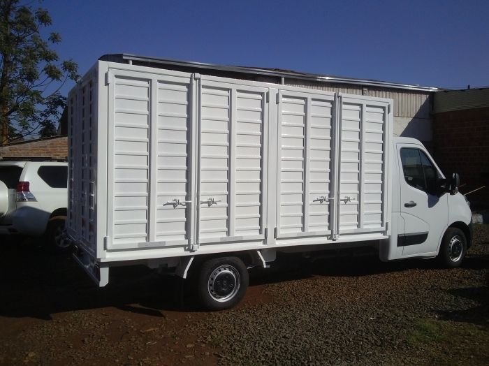 Camión de carga blanco con carrocería cuadrada, estacionado al aire libre.