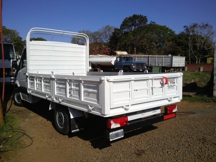 Camión blanco de plataforma, estacionado al aire libre. Vista trasera.