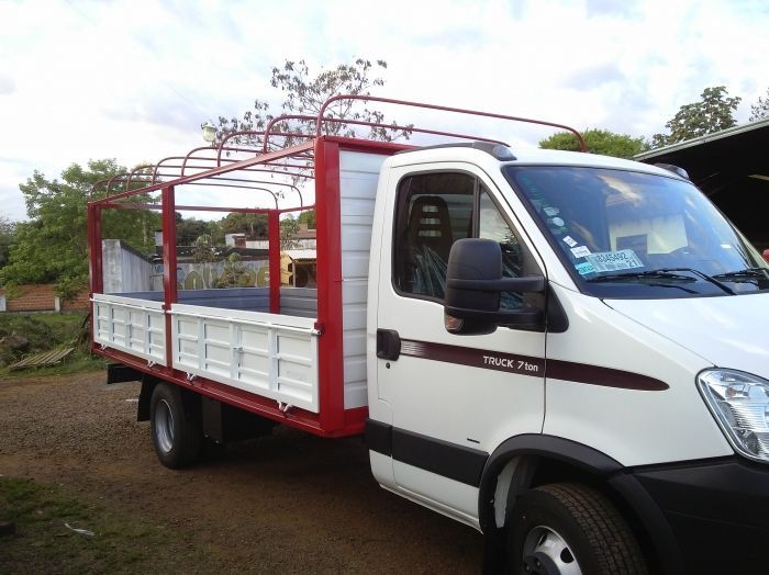 Camión utilitario blanco y rojo con caja de carga, estacionado al aire libre.