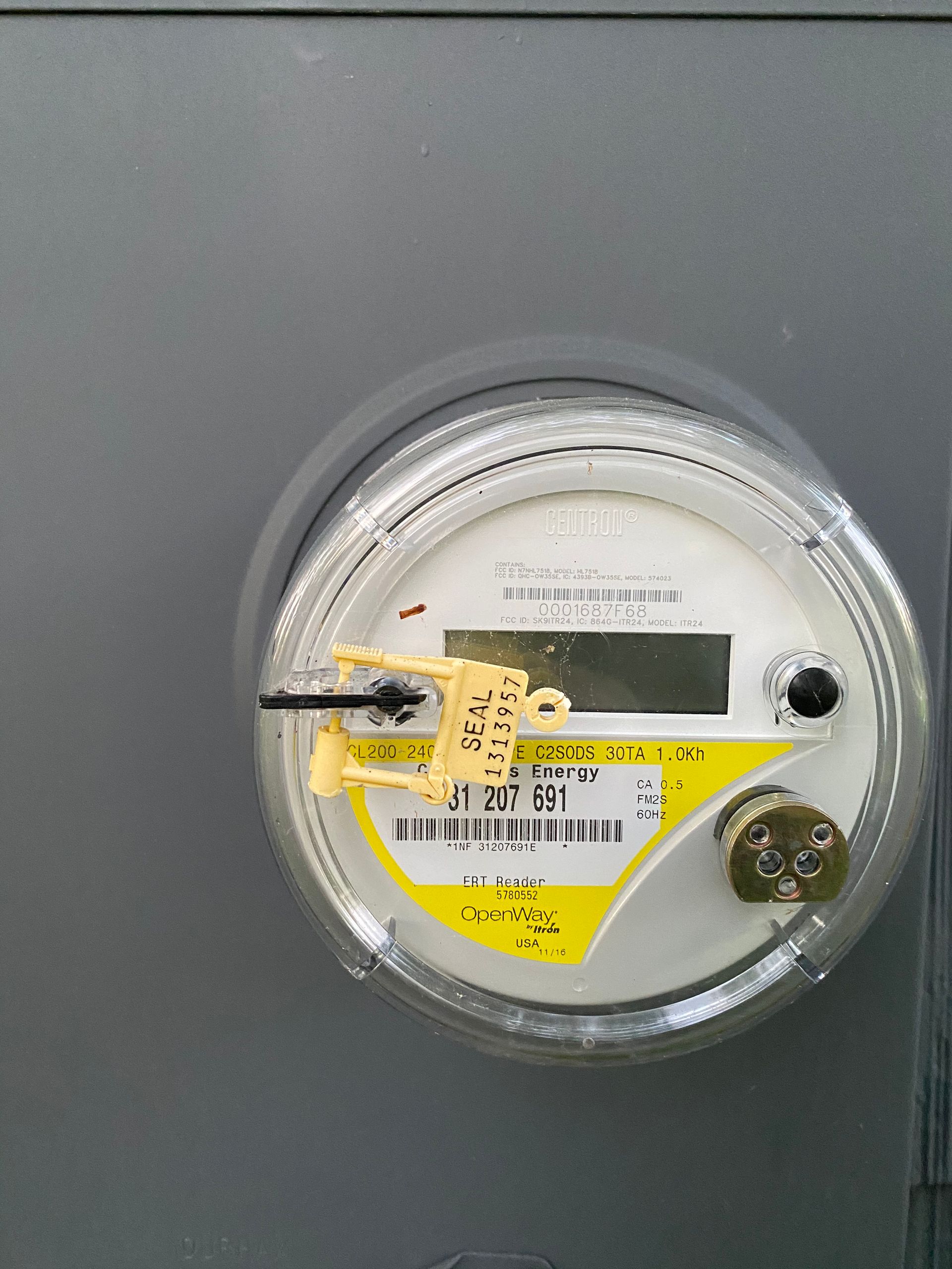 A close up of an electric meter with a yellow seal on it