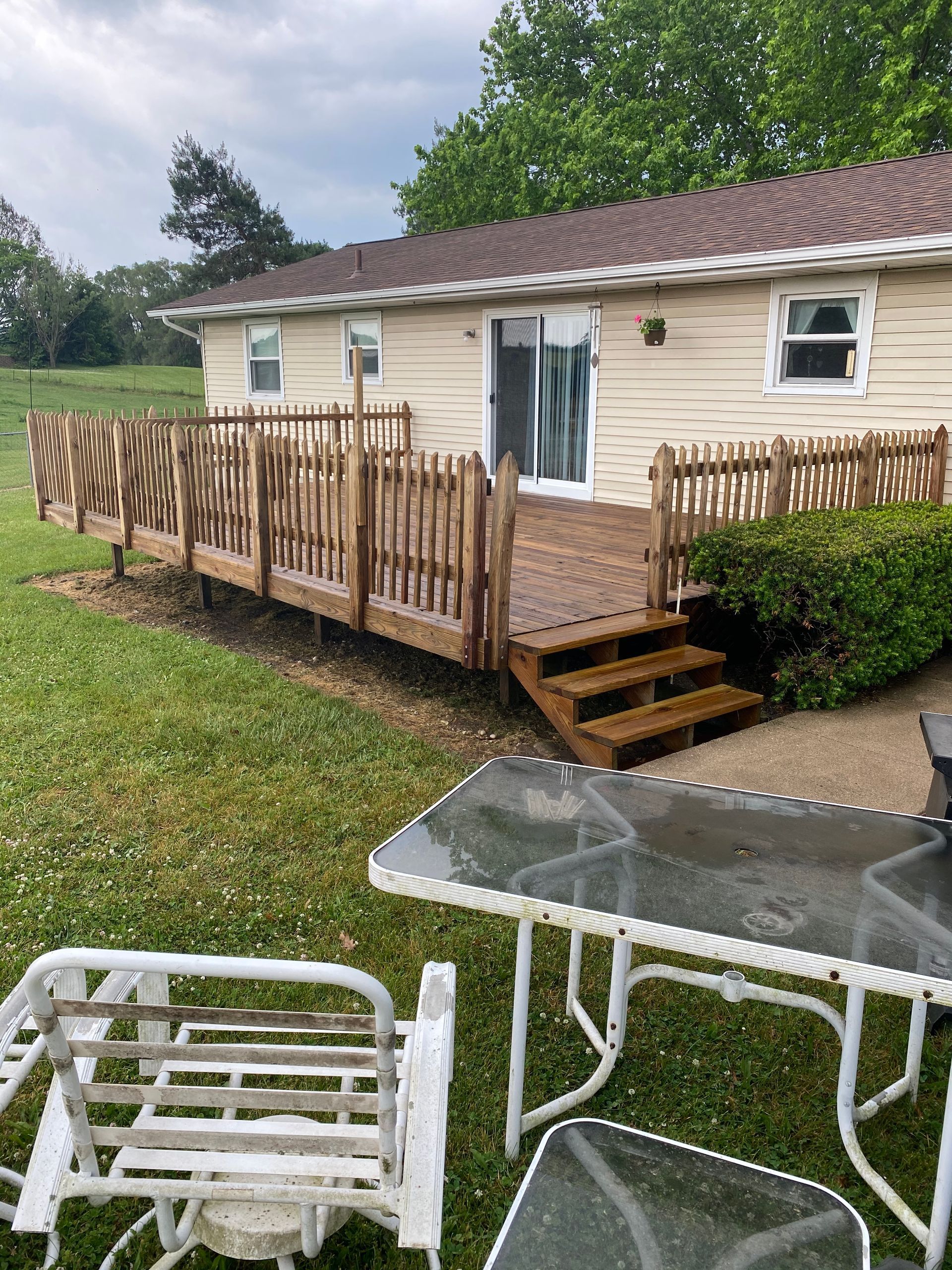 A house with a deck and a table and chairs in front of it.