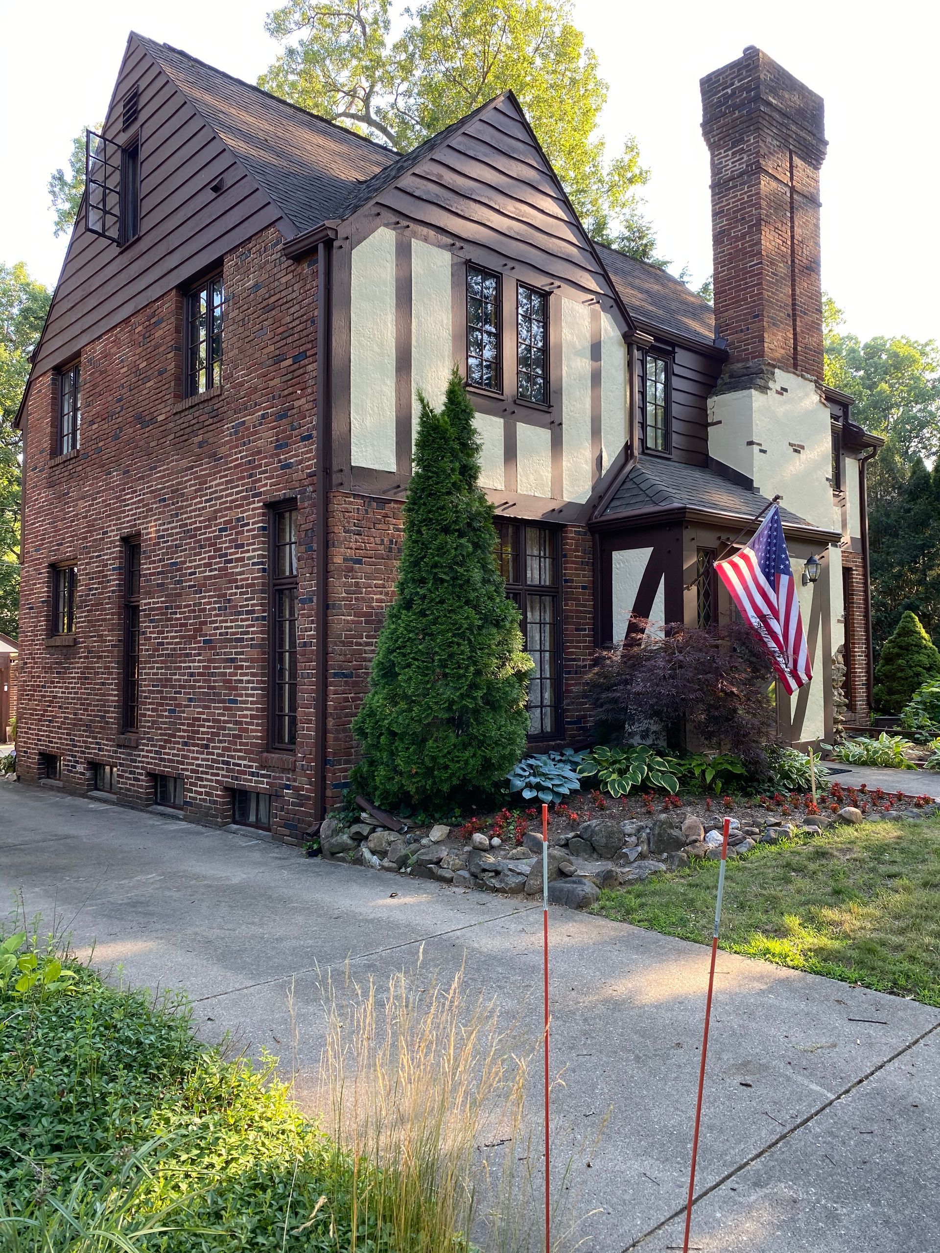A large brick house with a chimney and an american flag in front of it.