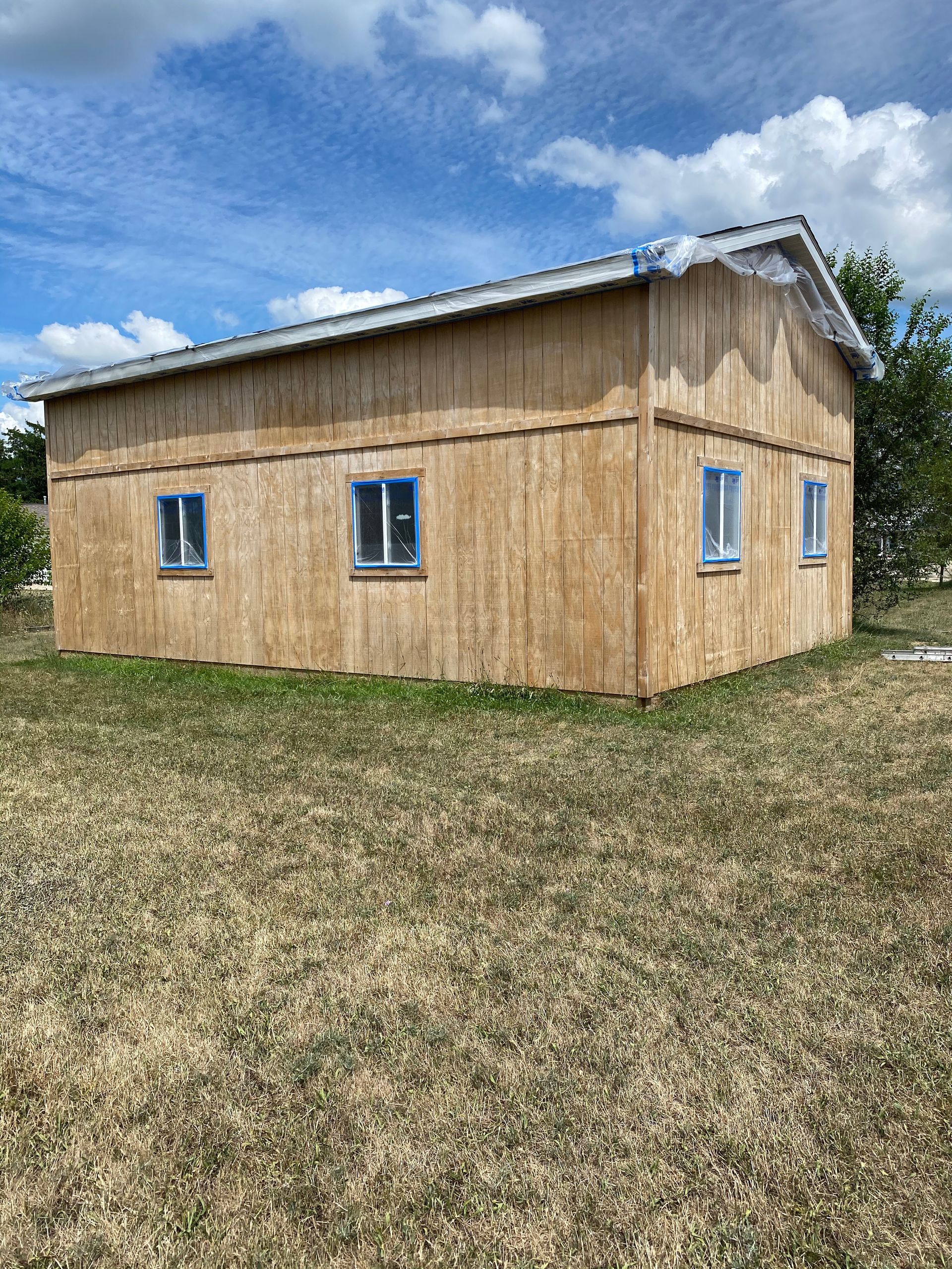 A small wooden house is sitting in the middle of a grassy field.