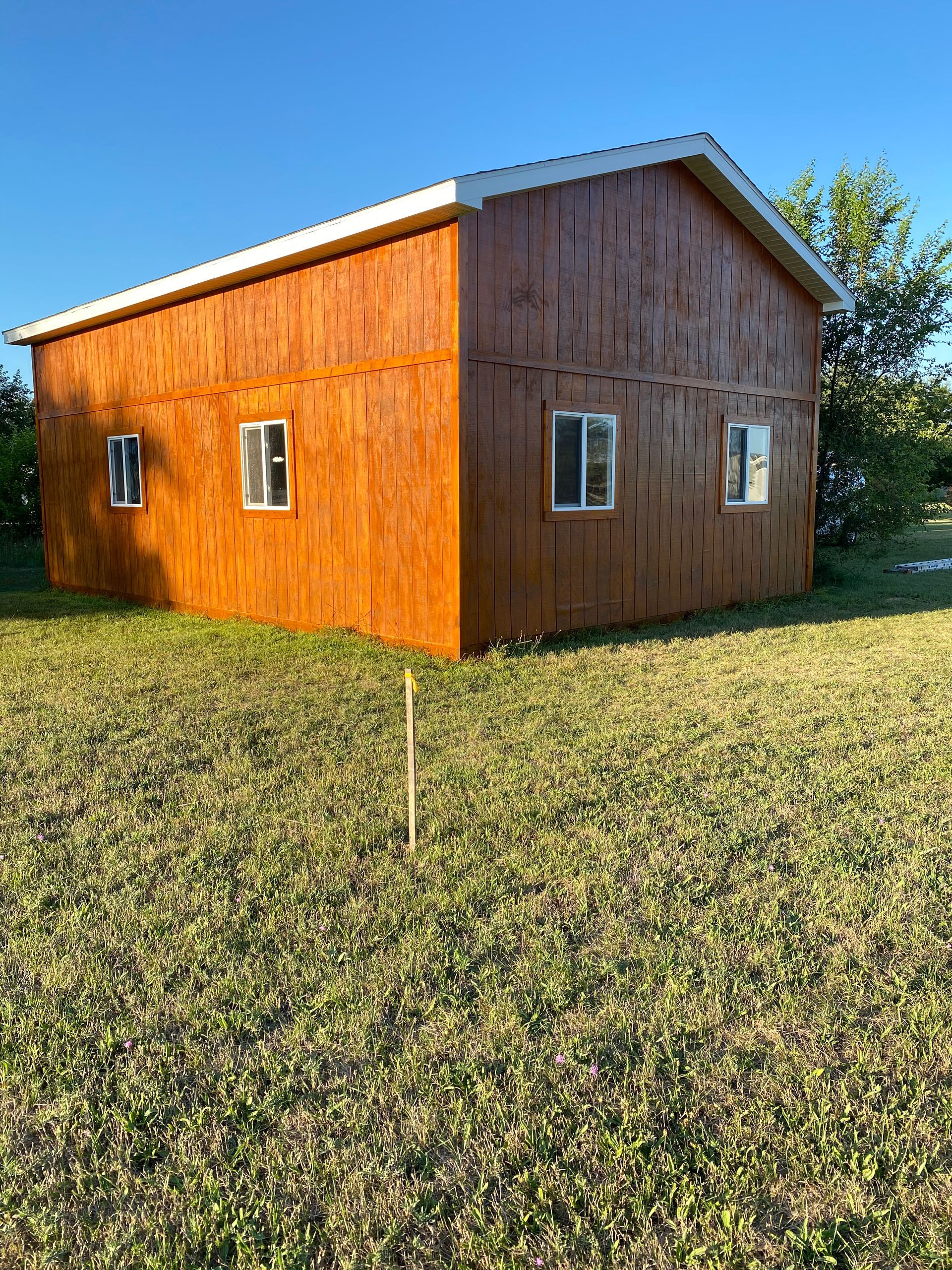 A small wooden house is sitting in the middle of a grassy field.