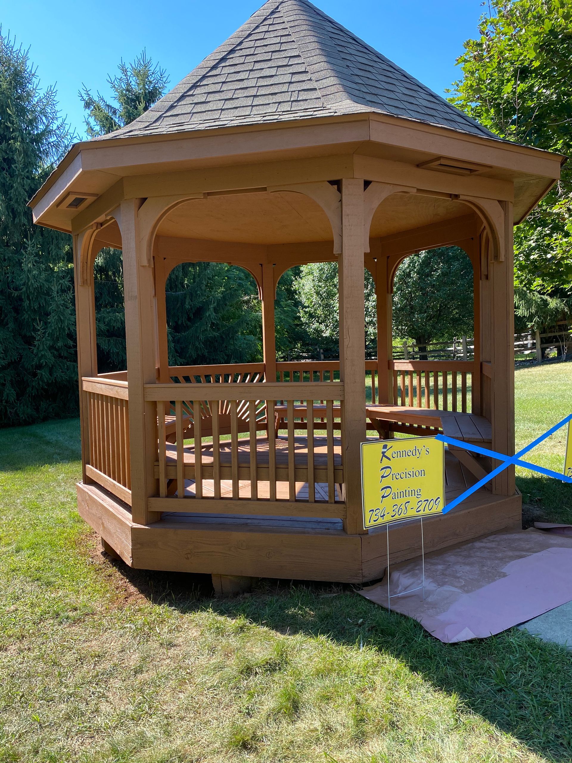 A wooden gazebo is sitting in the middle of a lush green field.