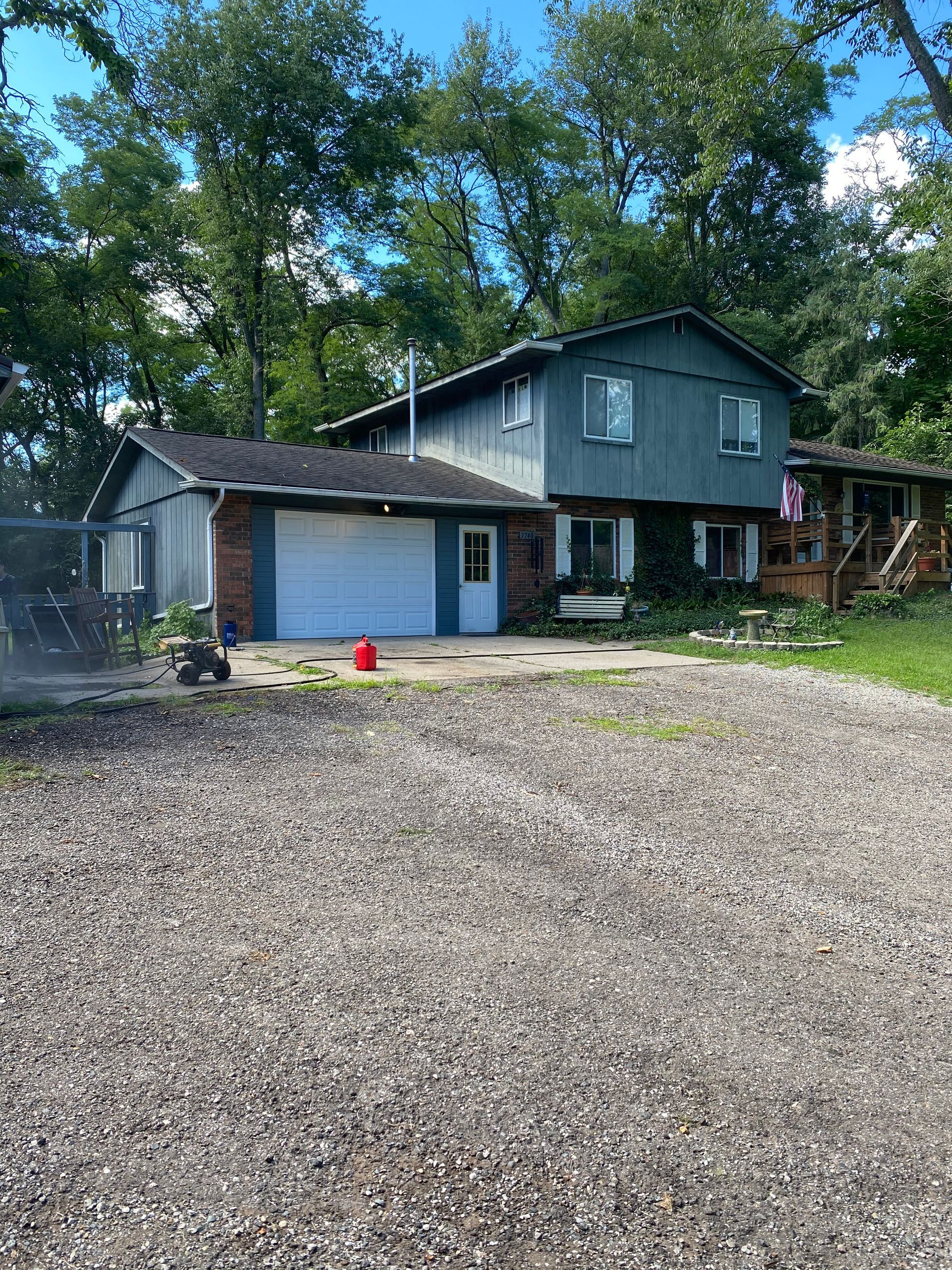 A large house with a garage and a gravel driveway in front of it.
