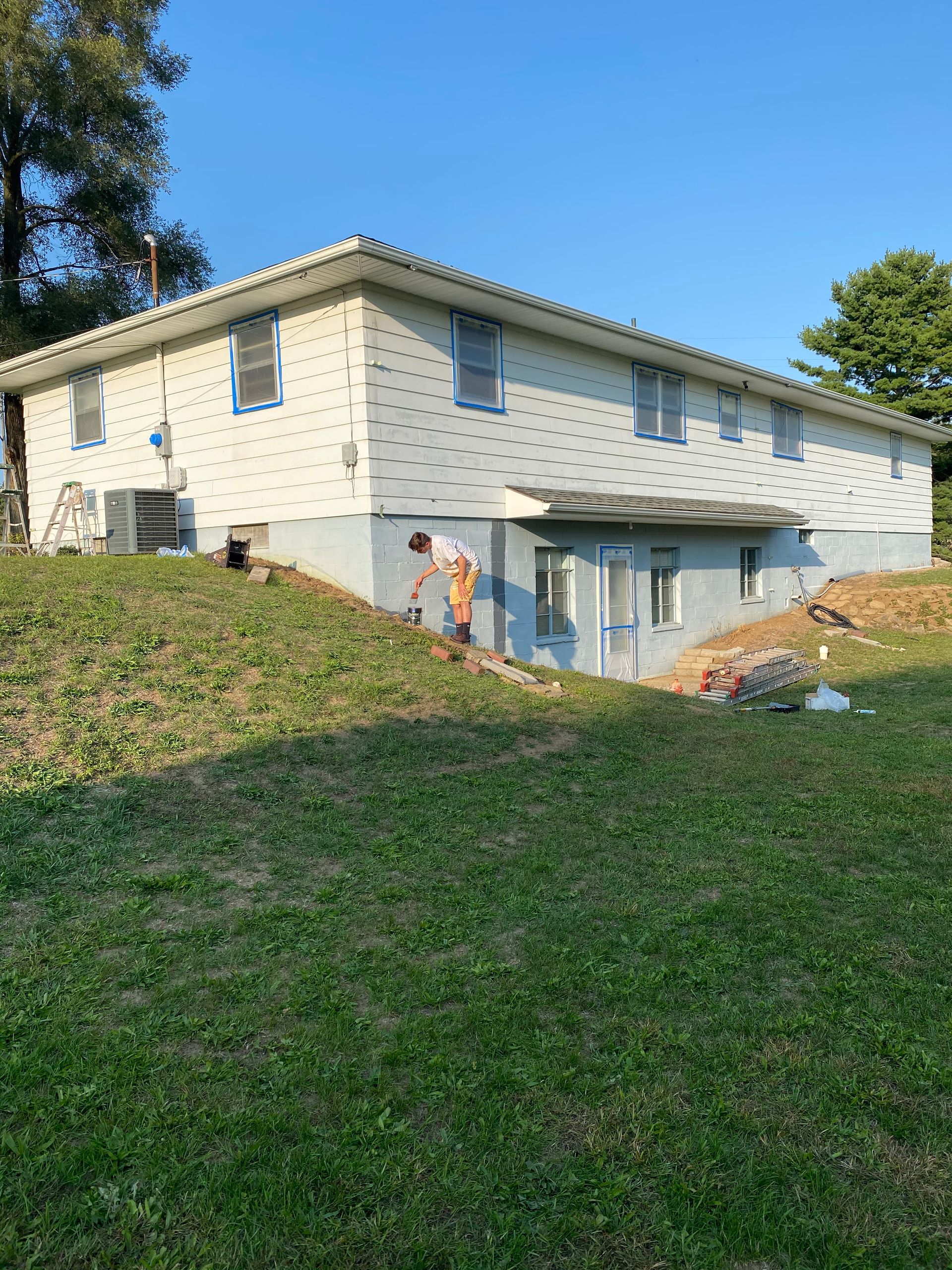 A man is standing on a grassy hill in front of a house.