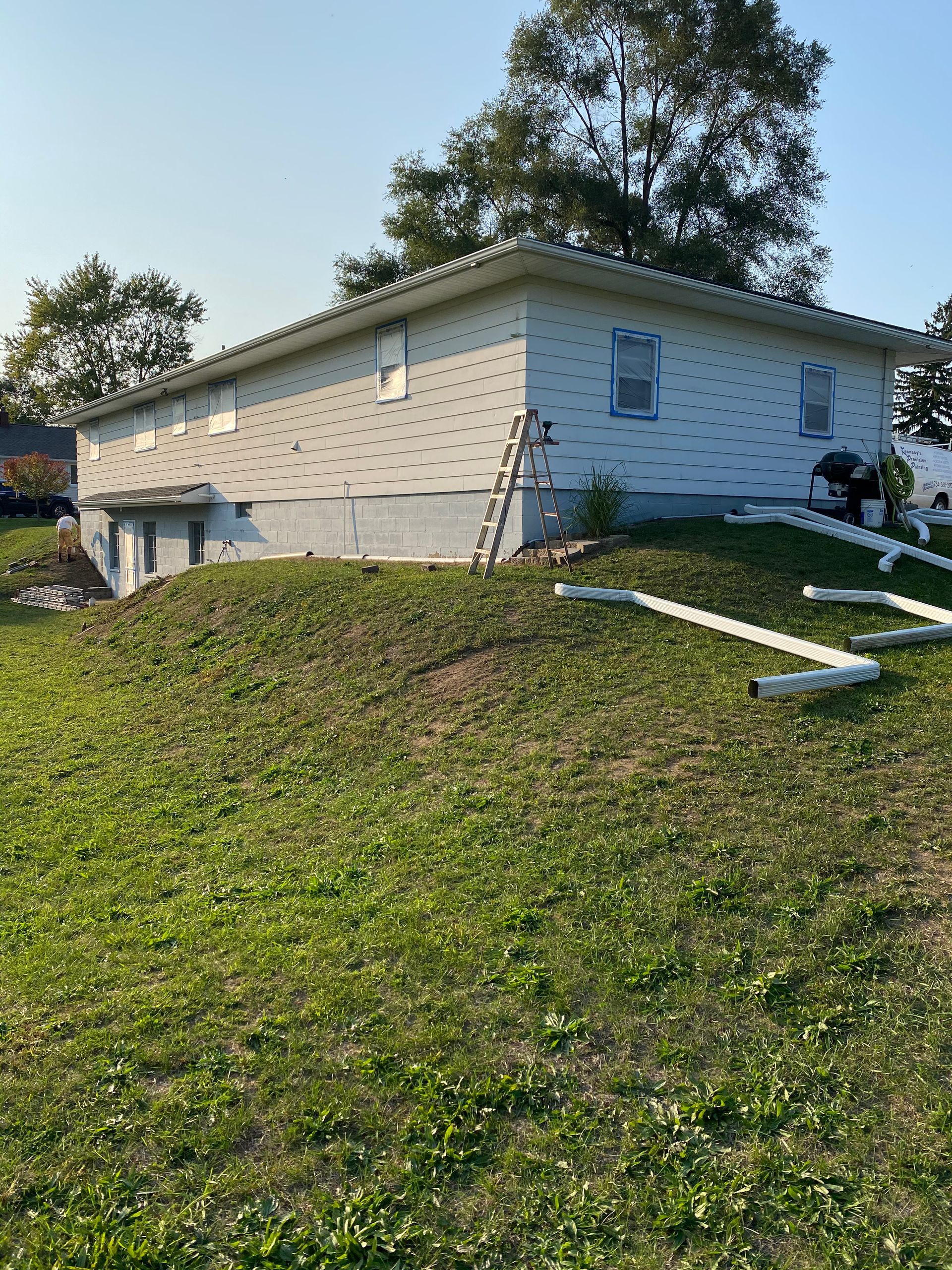 A white house is sitting on top of a grassy hill.