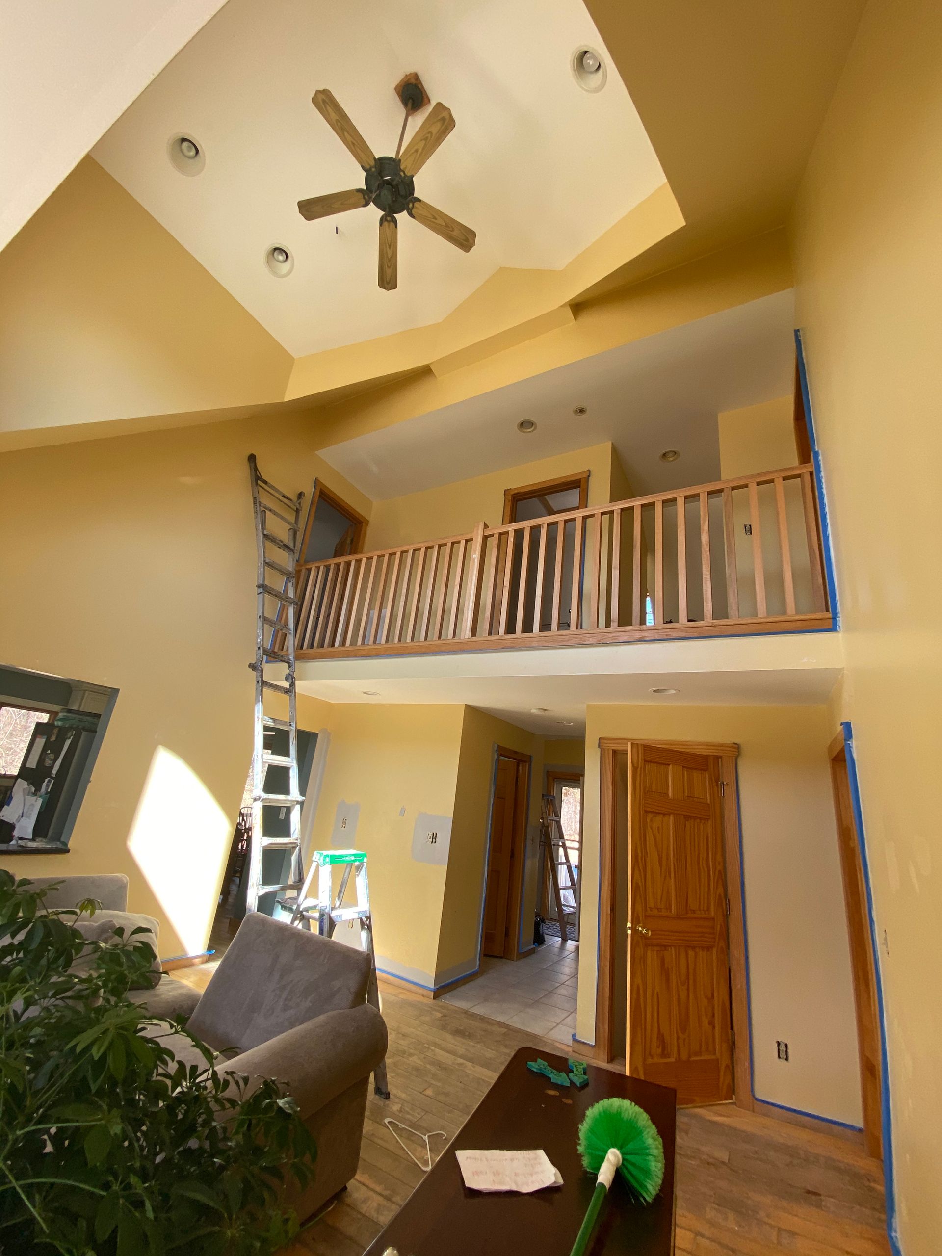 A living room with a balcony and a ceiling fan
