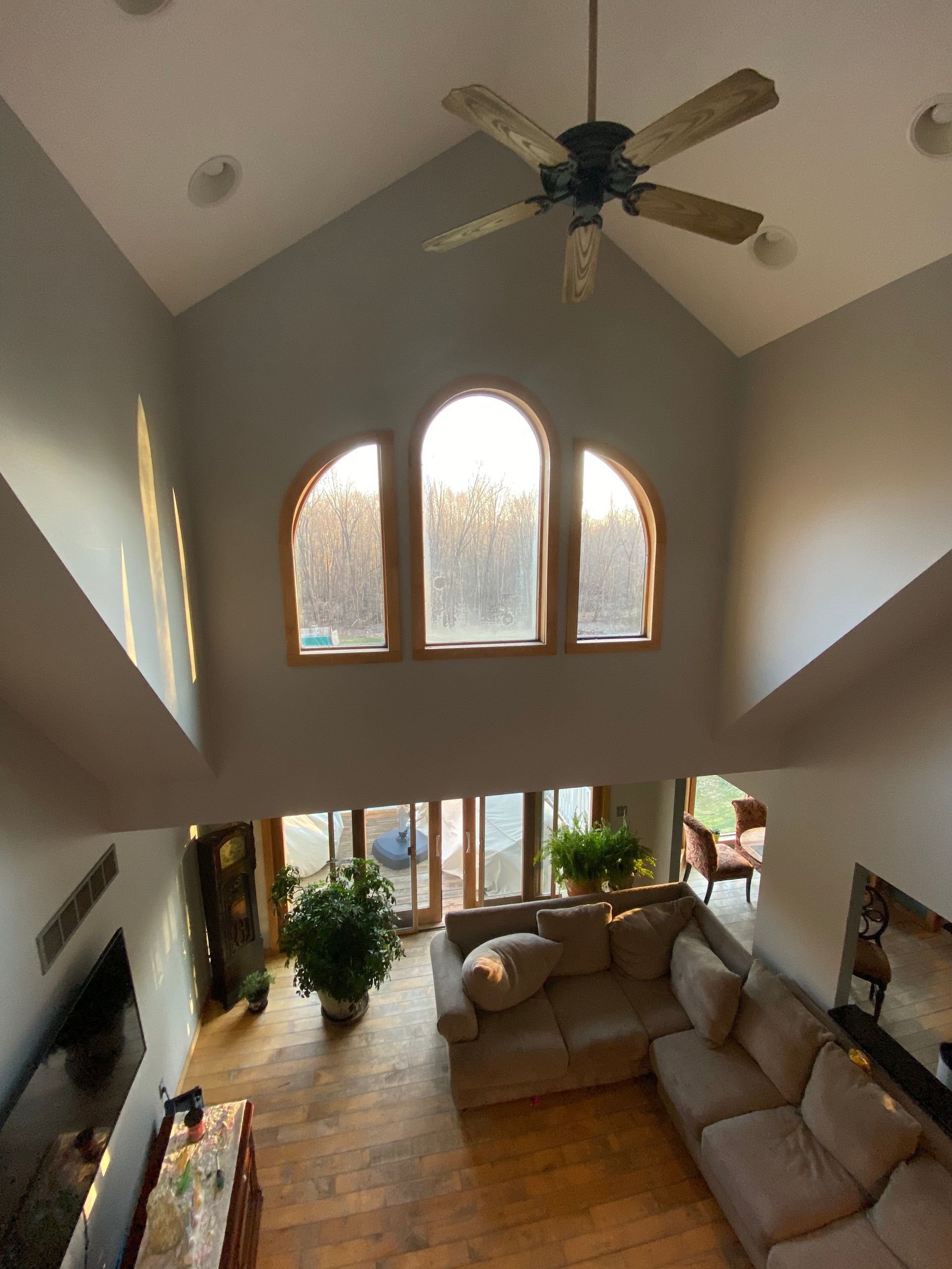 A living room with a lot of windows and a ceiling fan