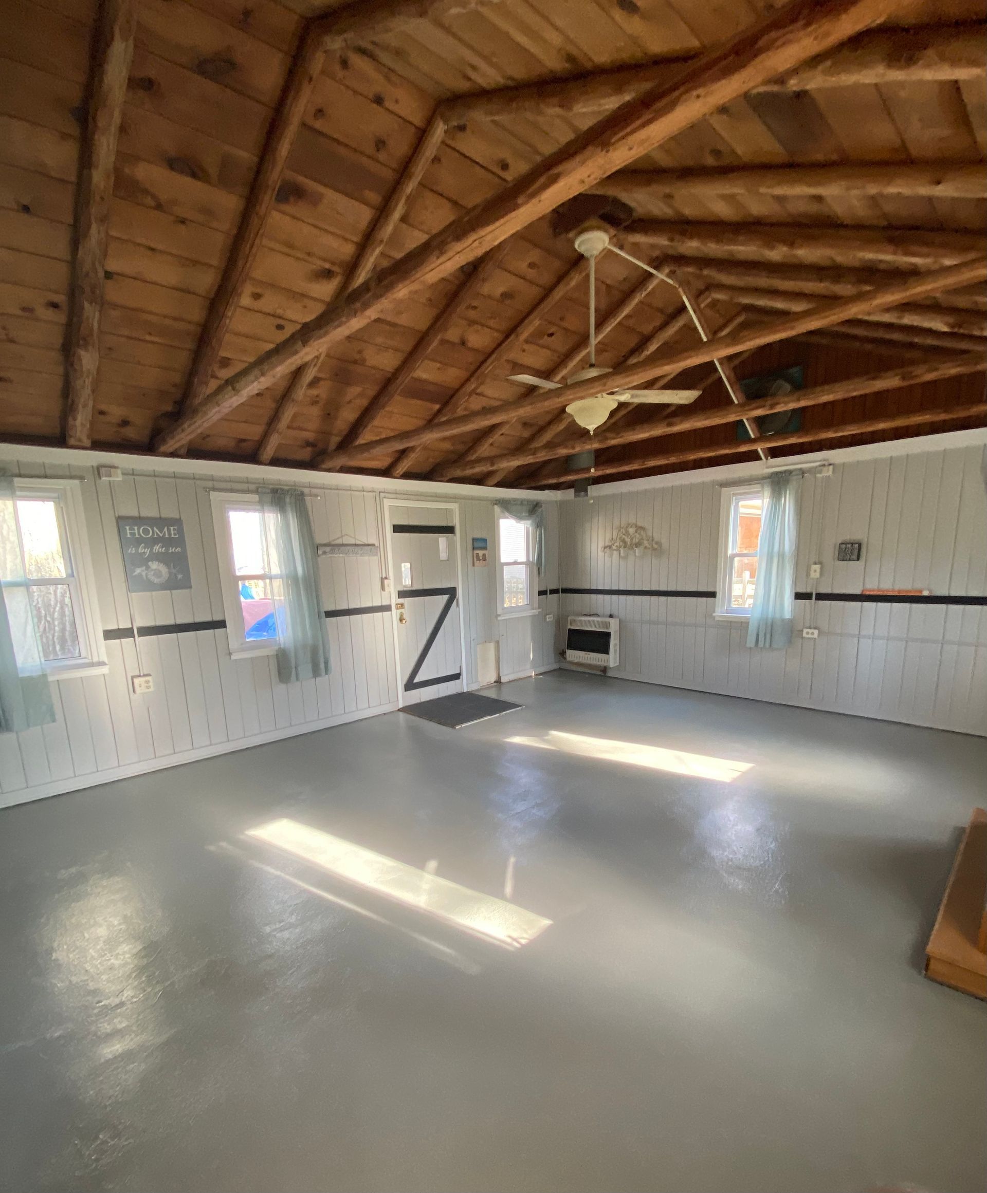A large empty room with a wooden ceiling and a ceiling fan.
