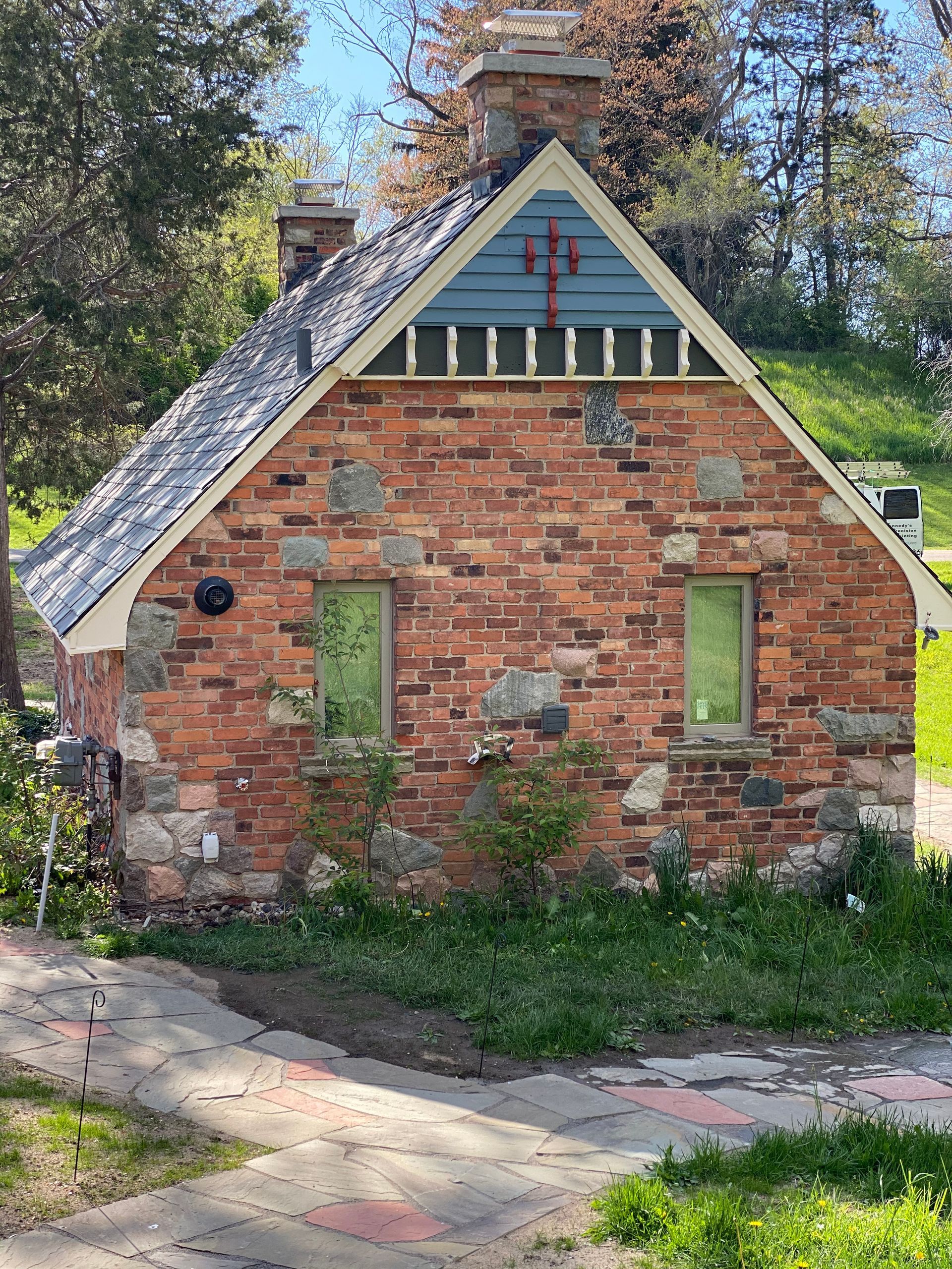A small brick house with a blue roof and a green window.