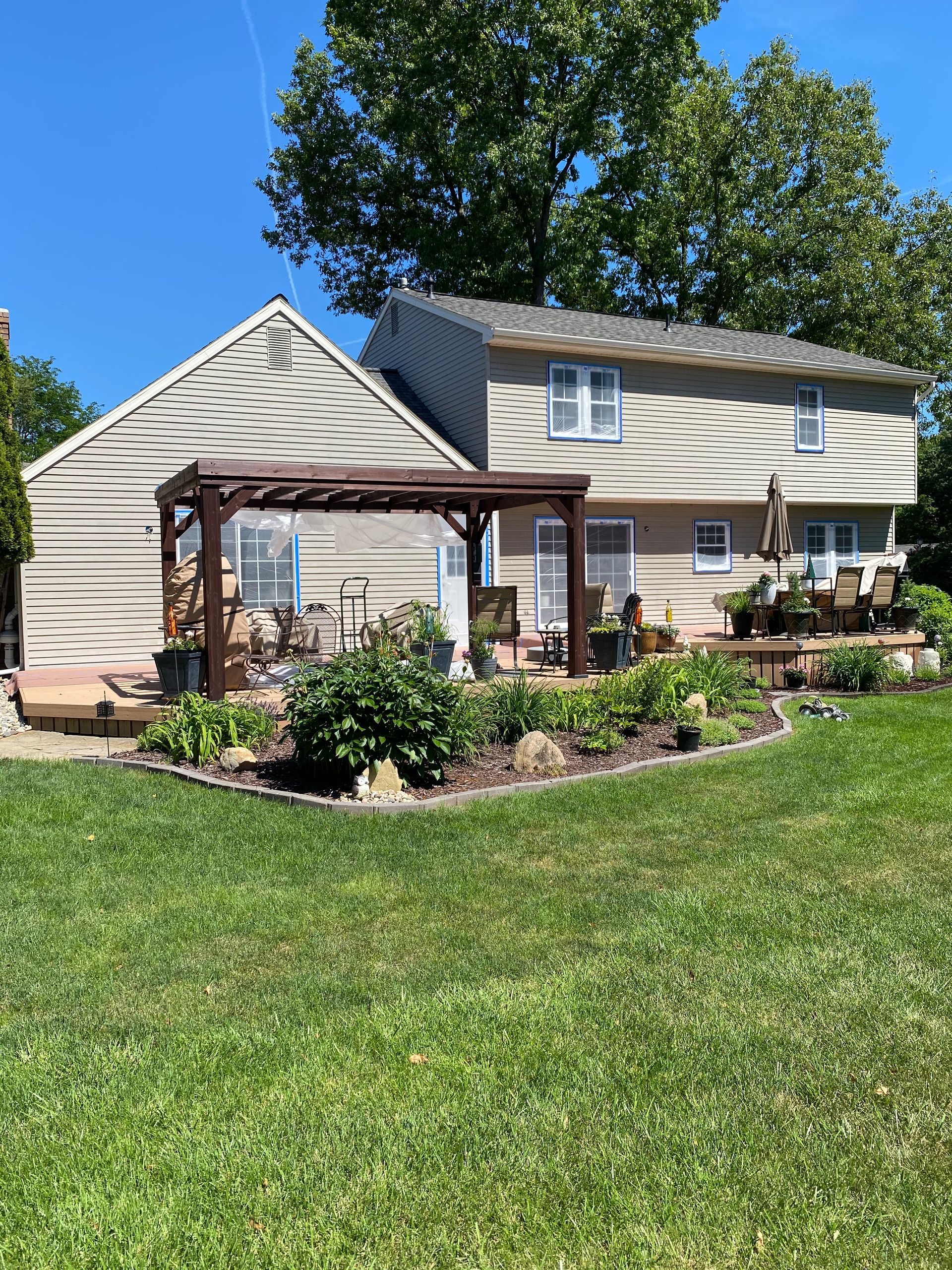 A house with a pergola in the backyard on a sunny day.