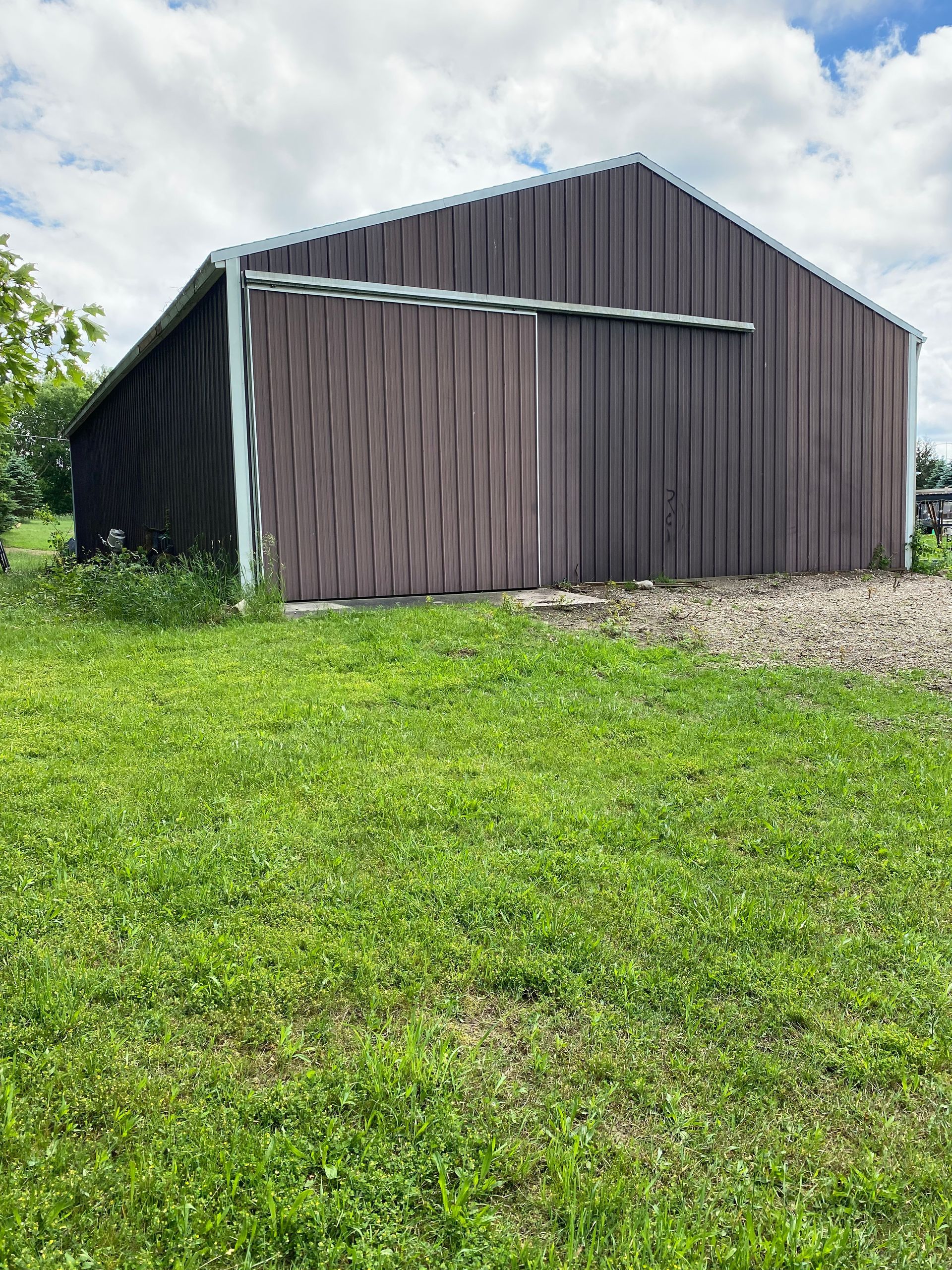 A large barn is sitting in the middle of a lush green field.