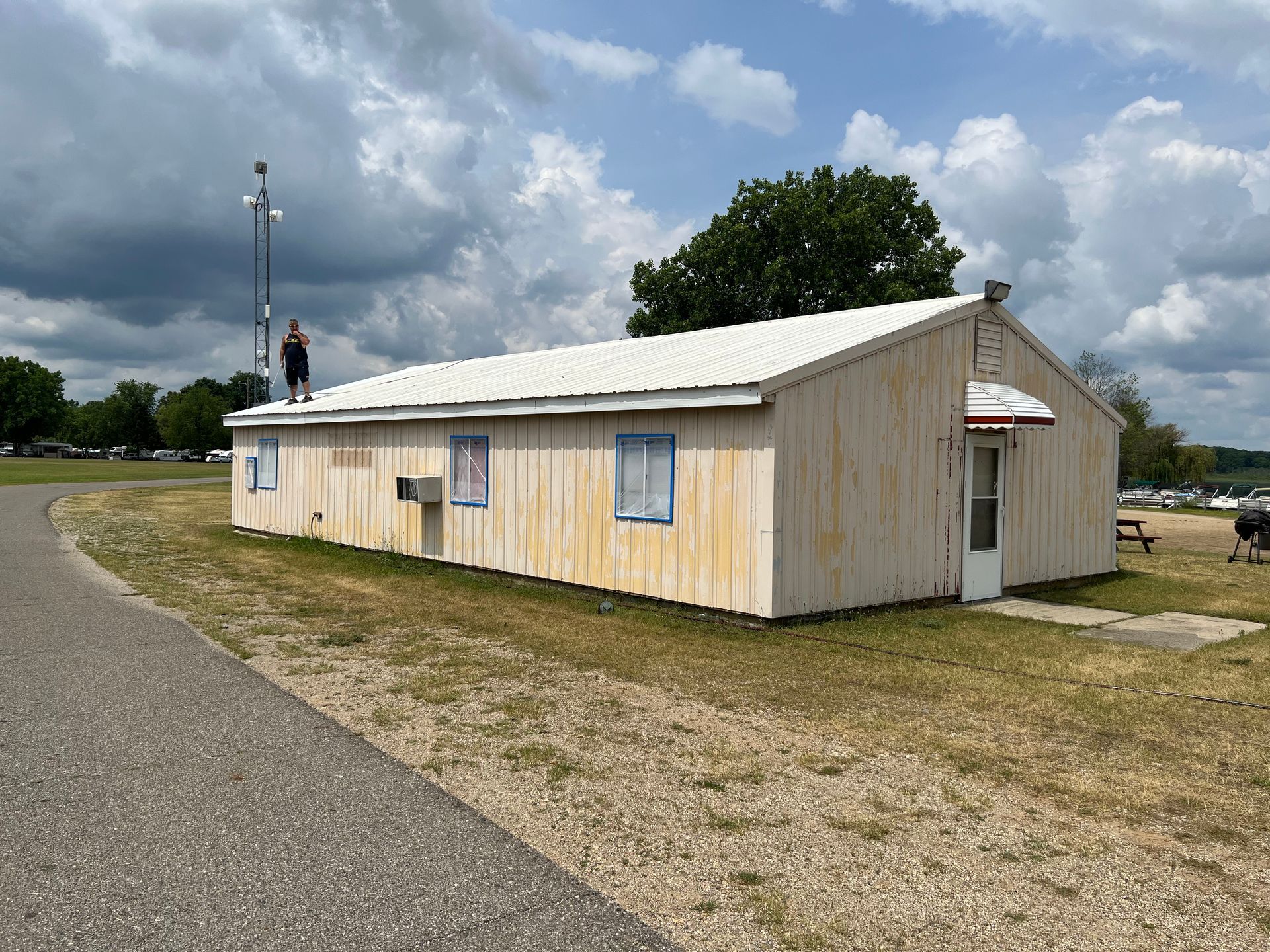 A man is standing on the roof of a small building.
