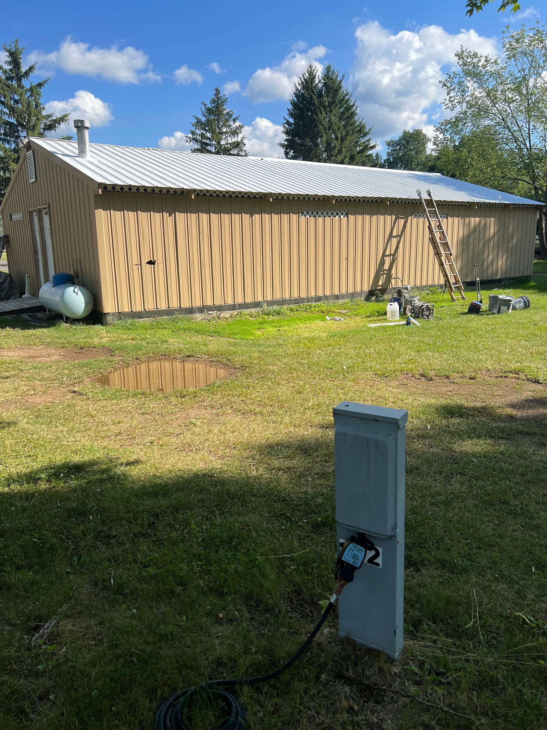 A house with a white roof is sitting in the middle of a grassy field.