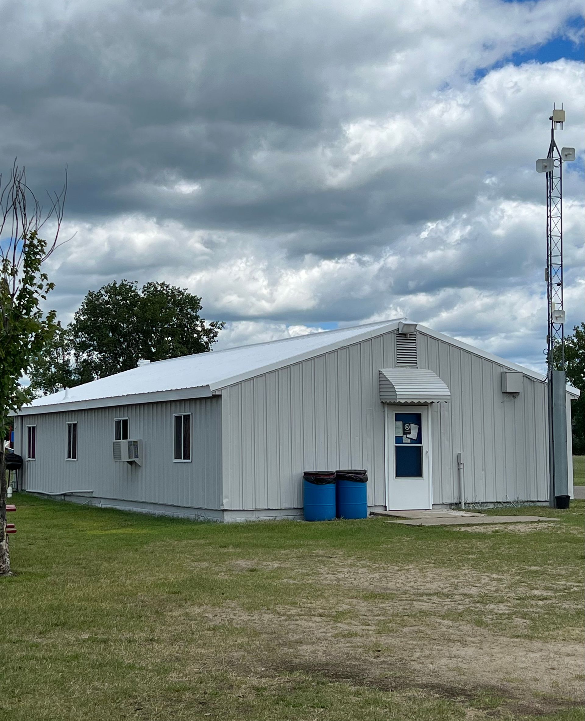 A white building with a blue trash can in front of it