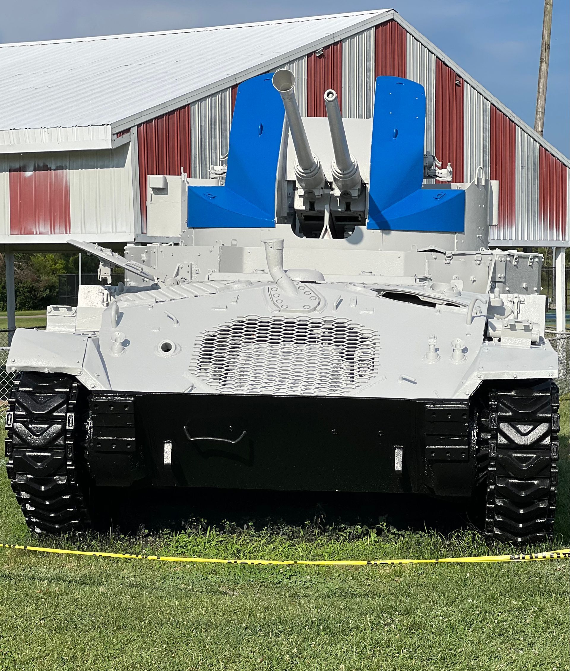 A white tank is parked in front of a red and white building.