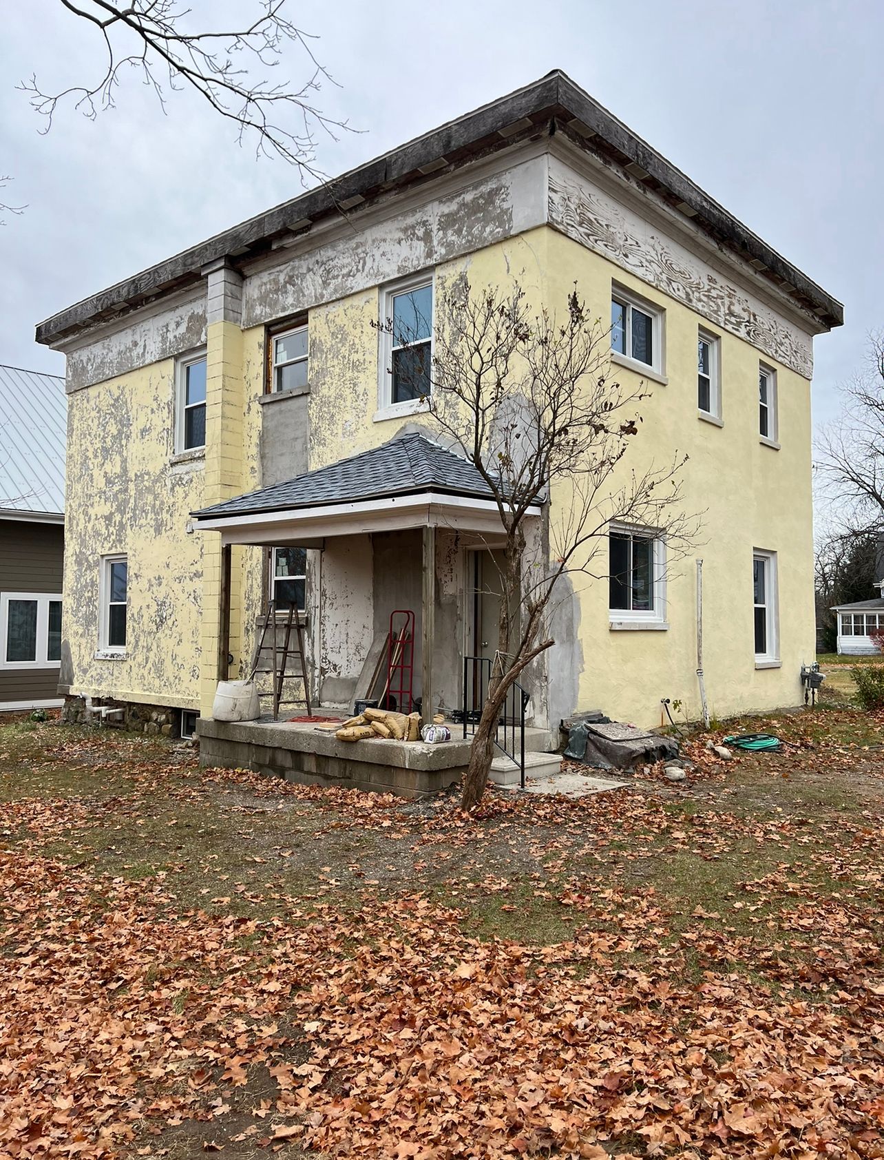 A yellow house is sitting in the middle of a field covered in leaves.