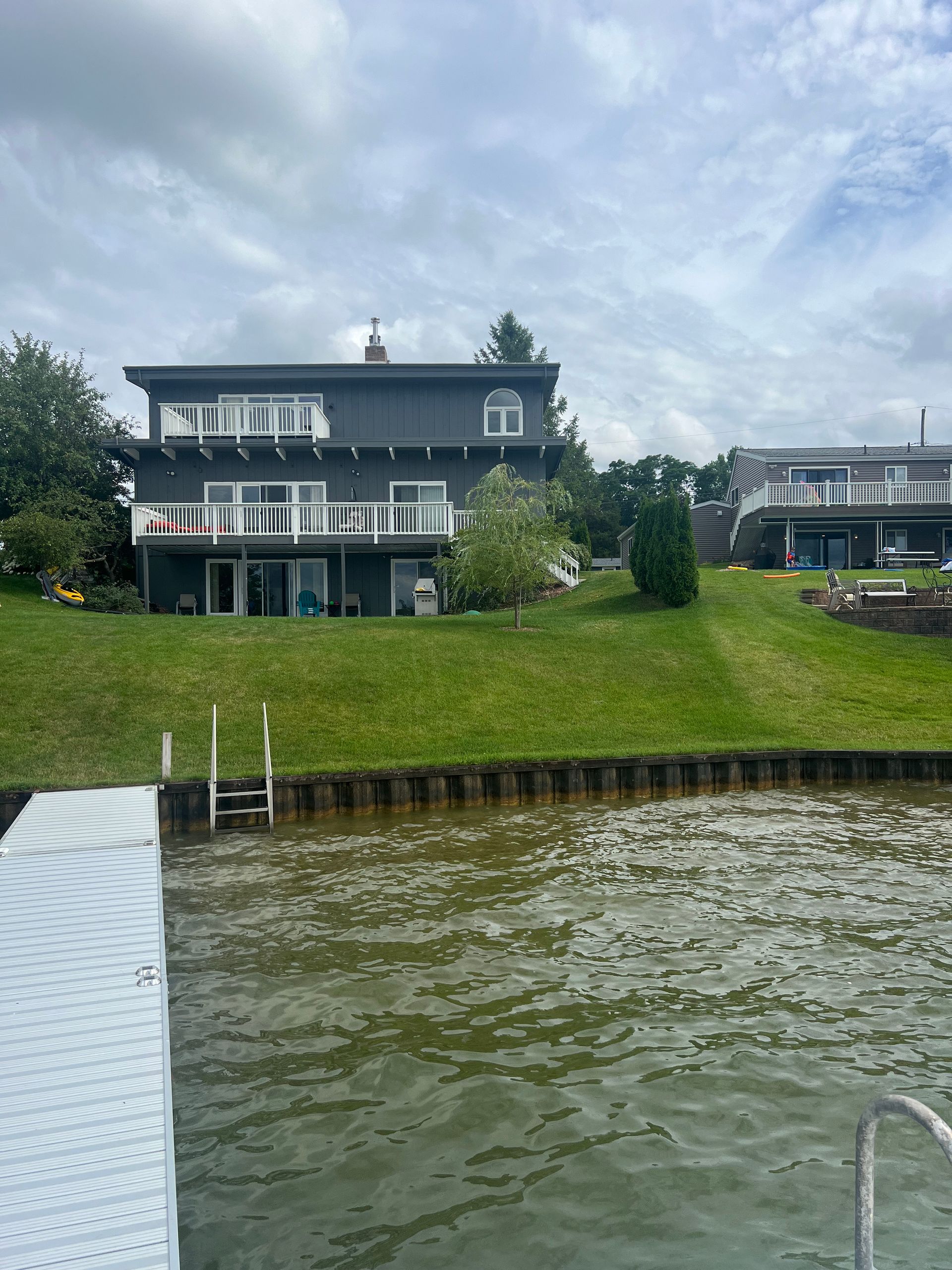 A large house sits on a hill overlooking a body of water.