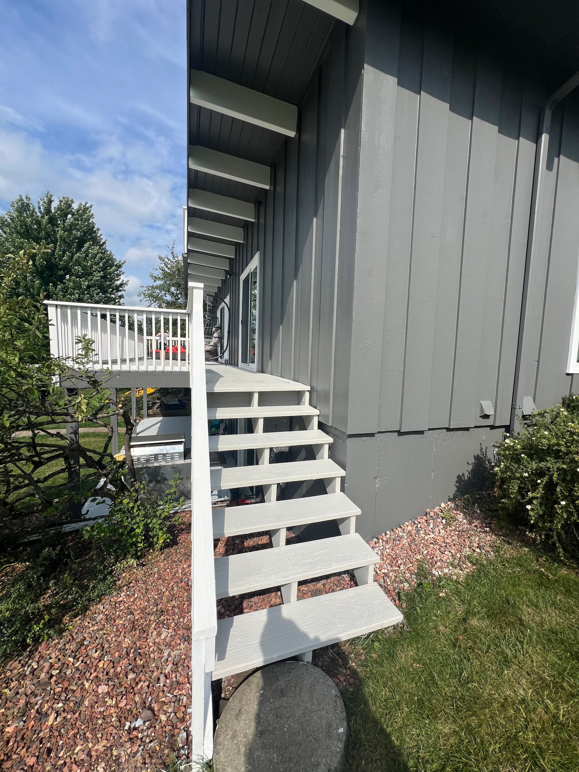 A picture of a house with stairs leading up to a deck.
