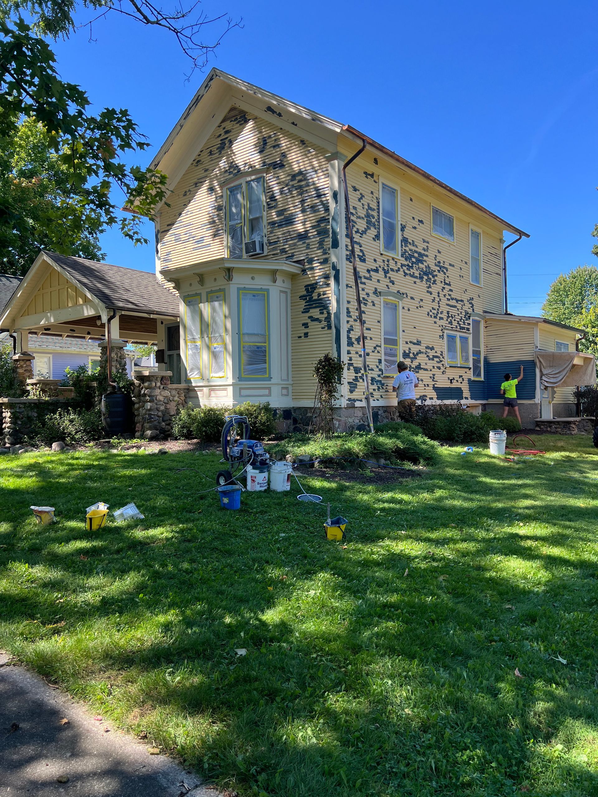 A house is being painted on a sunny day.