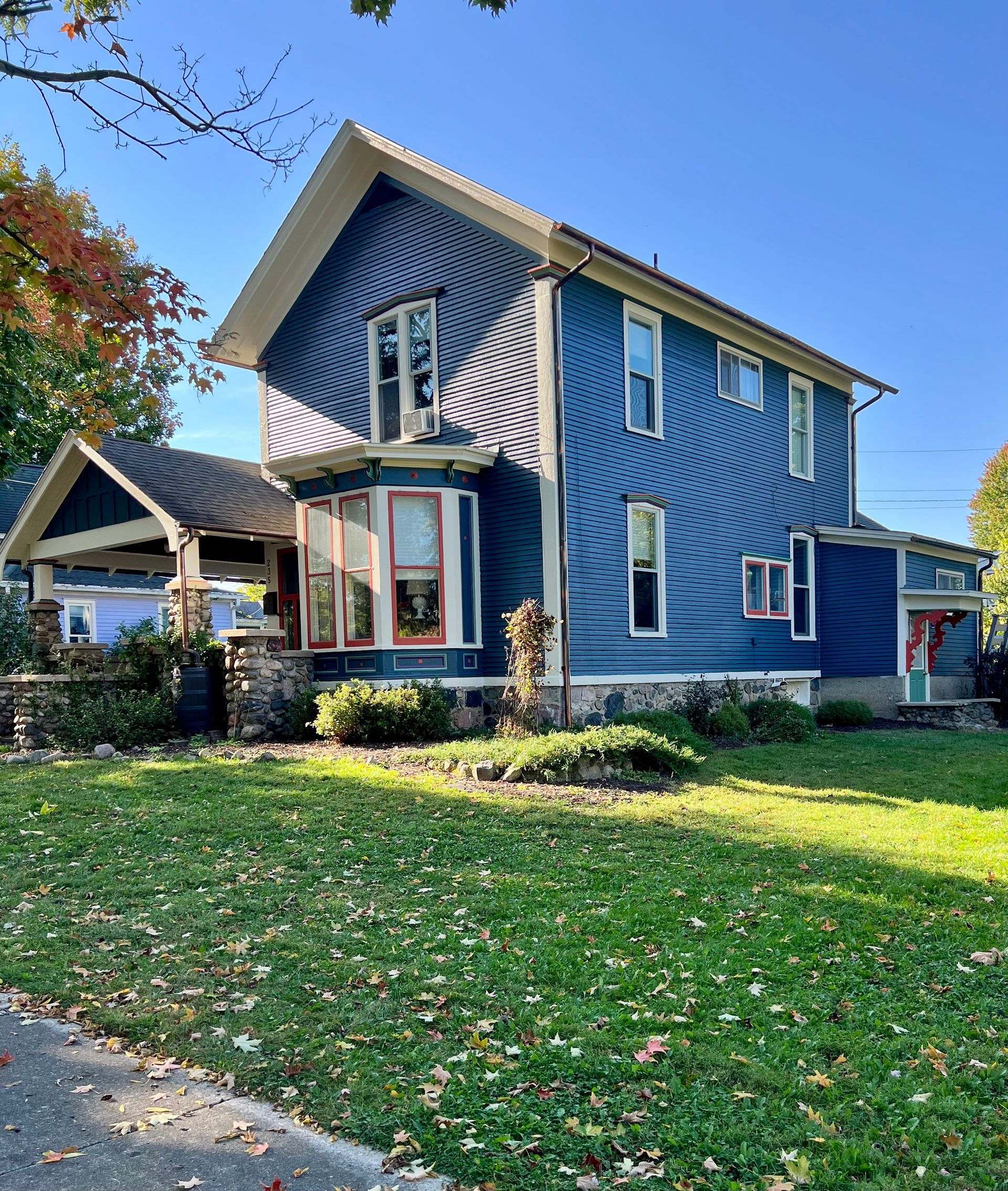 A large blue house with a large lawn in front of it.