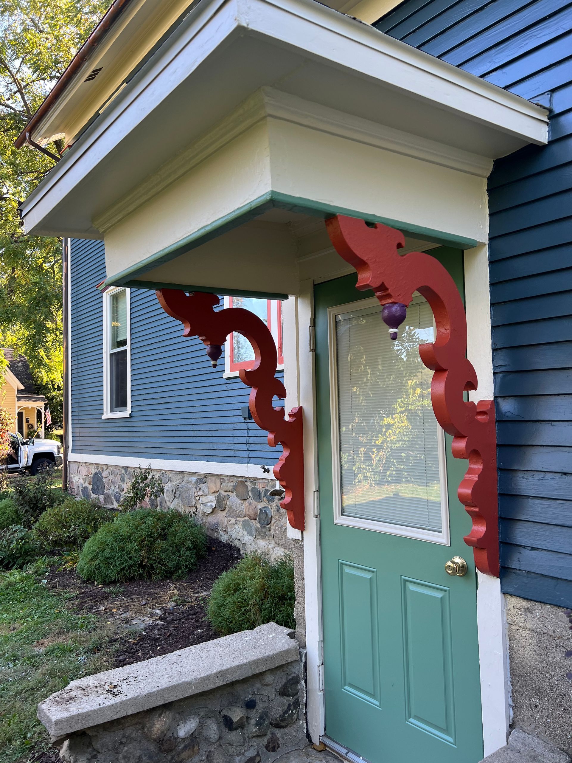 A blue house with a green door and a red porch