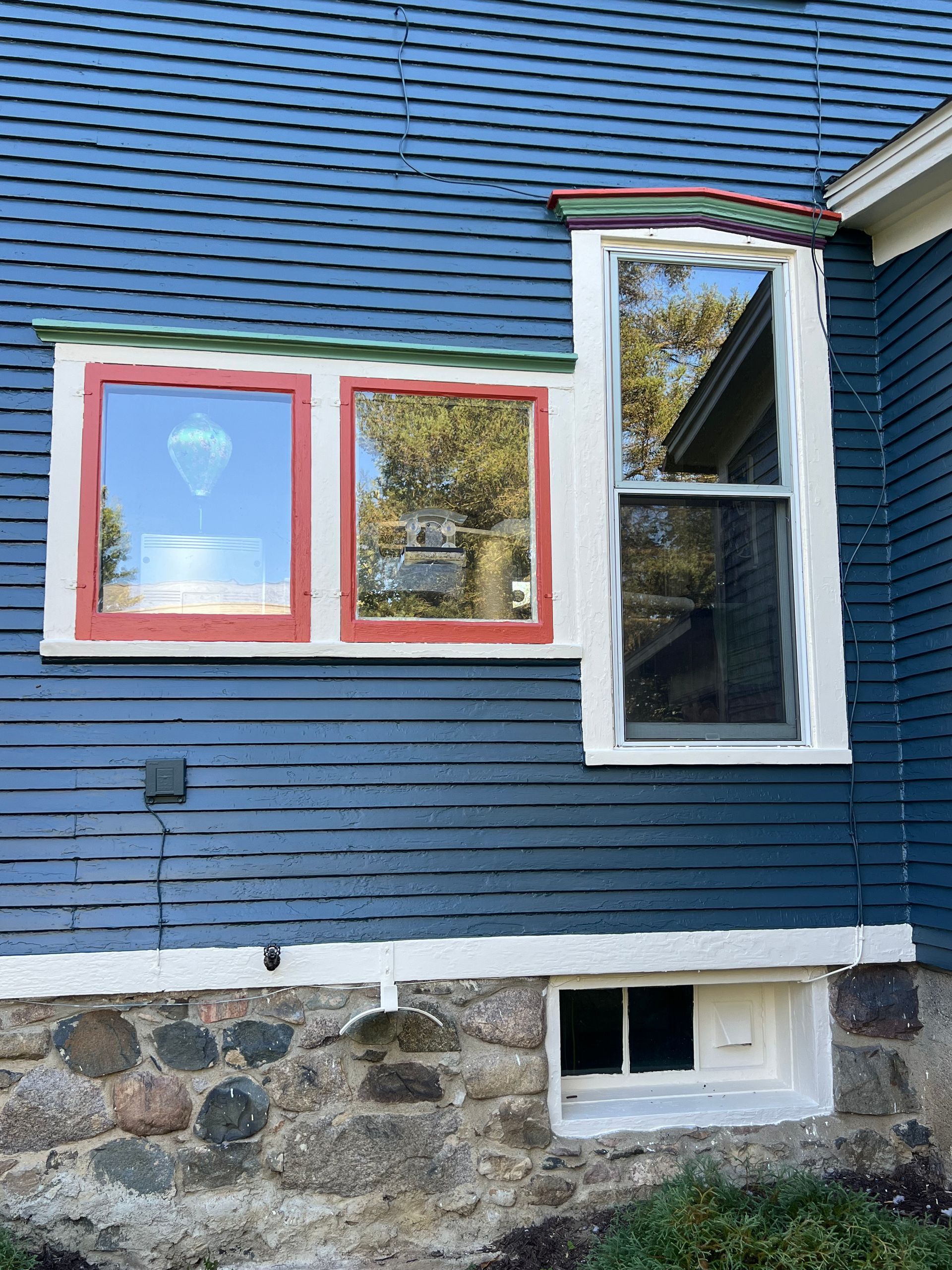 A blue house with two windows on the side of it.
